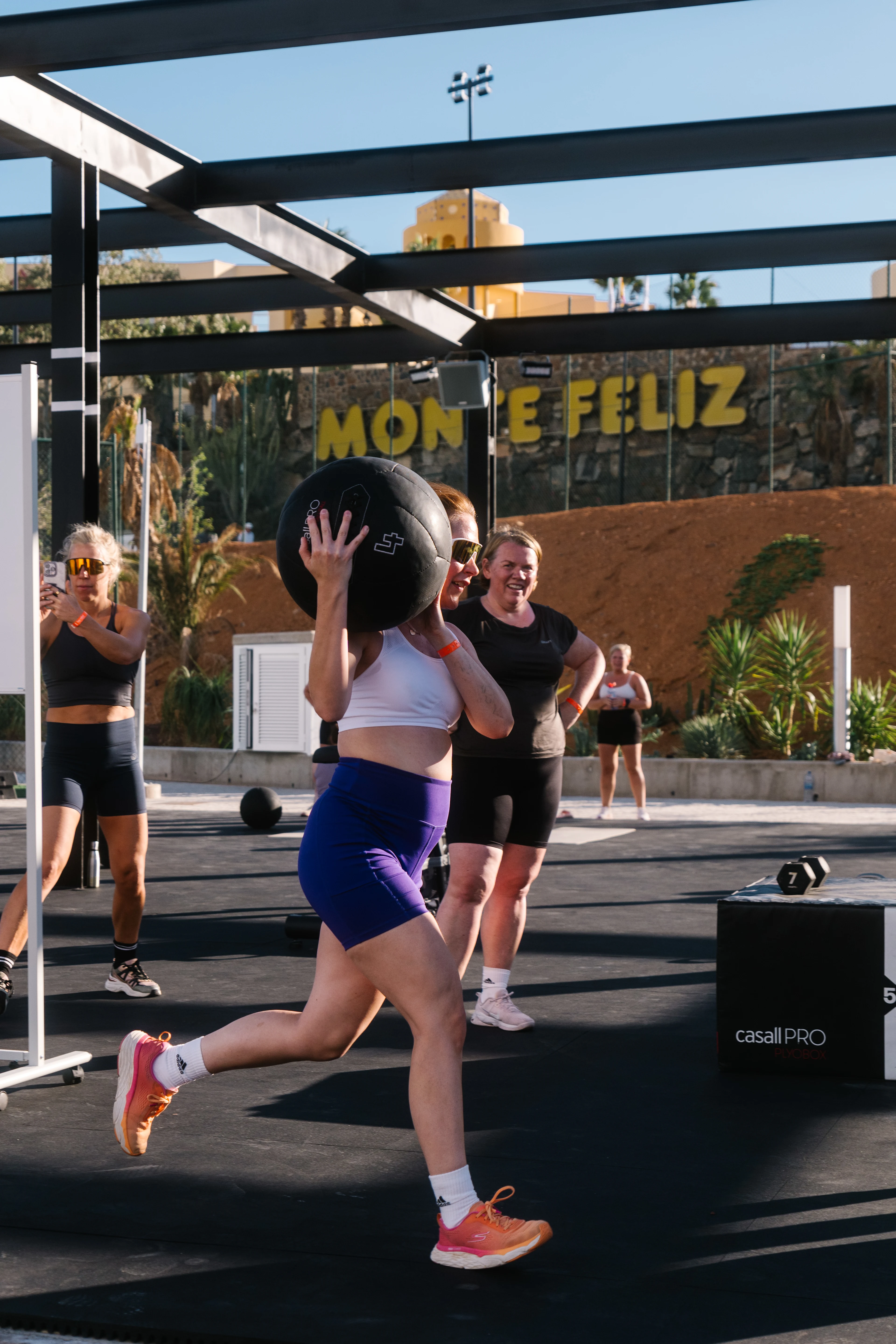 Dame iført lilla kort tights som løper med en medisinball i WOD Boxen på Monte Feliz.