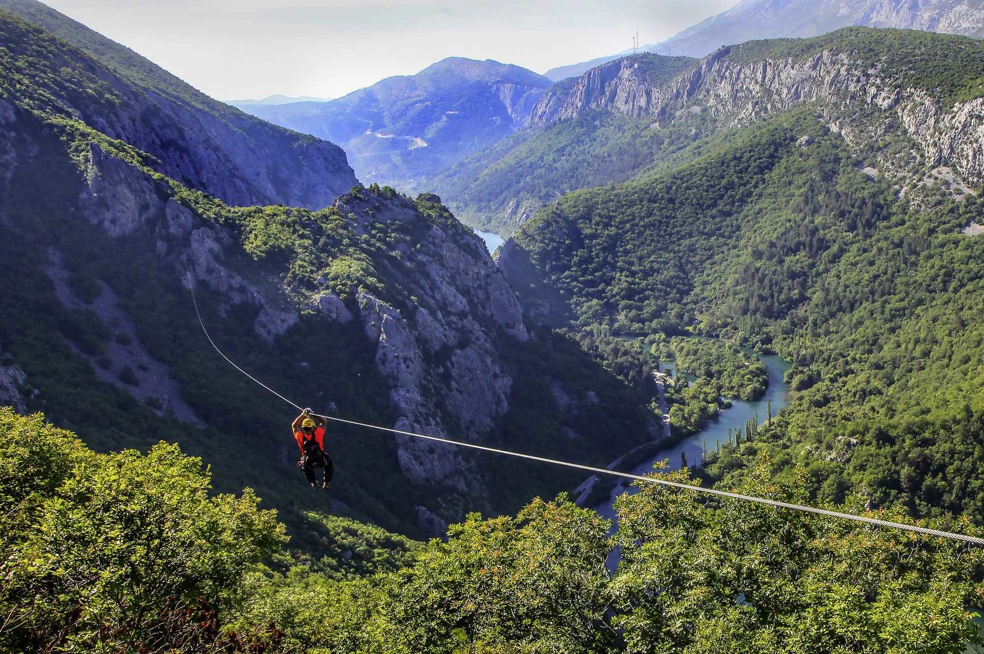 En som kjører en zipline mellom fjellene i Kroatia