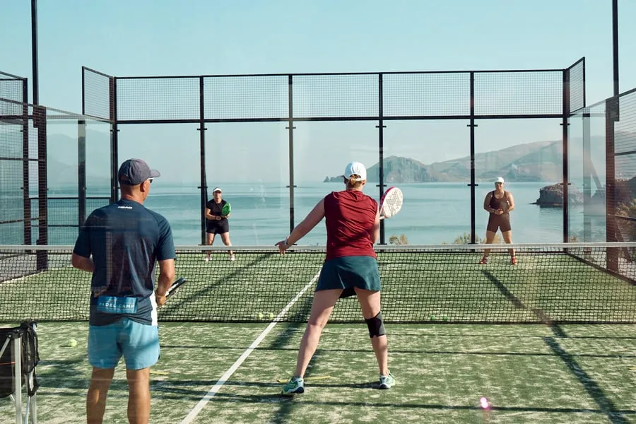 Människor som spelar padel med hav i bakgrunden 