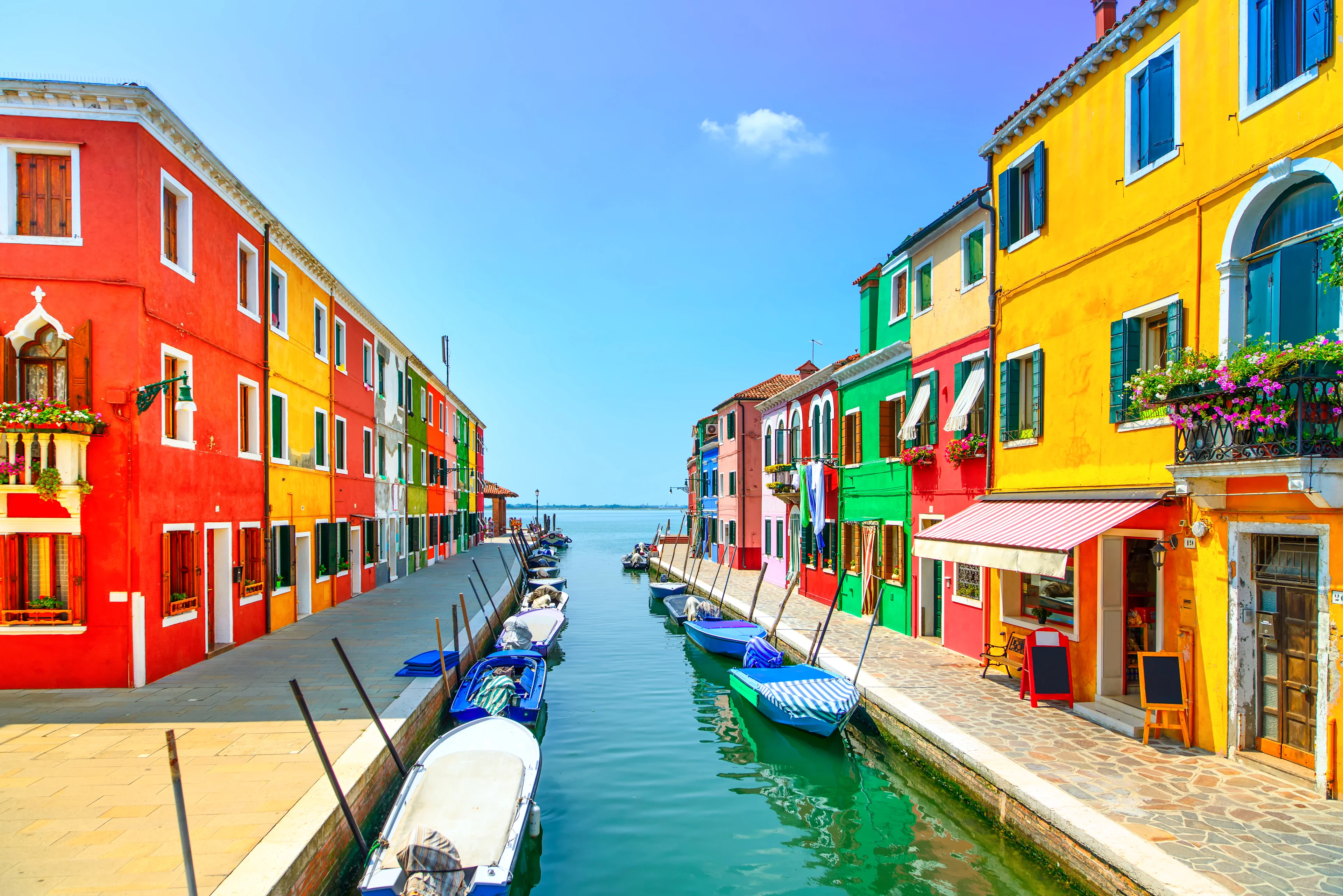 En charmig kanal med båtar och färgglada hus på Burano