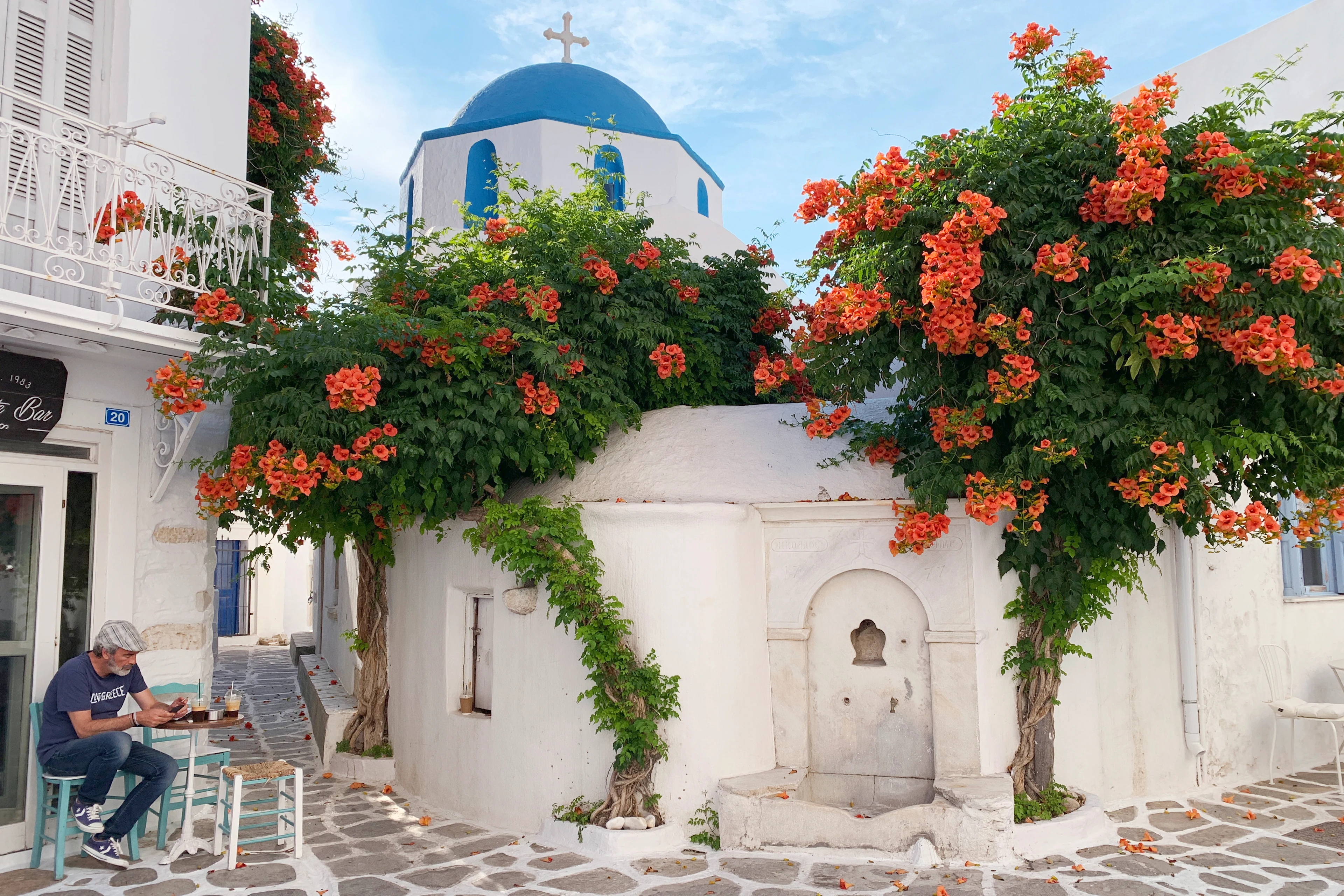 En vacker vitkalkad kyrka med blått tak och färgglada blommor