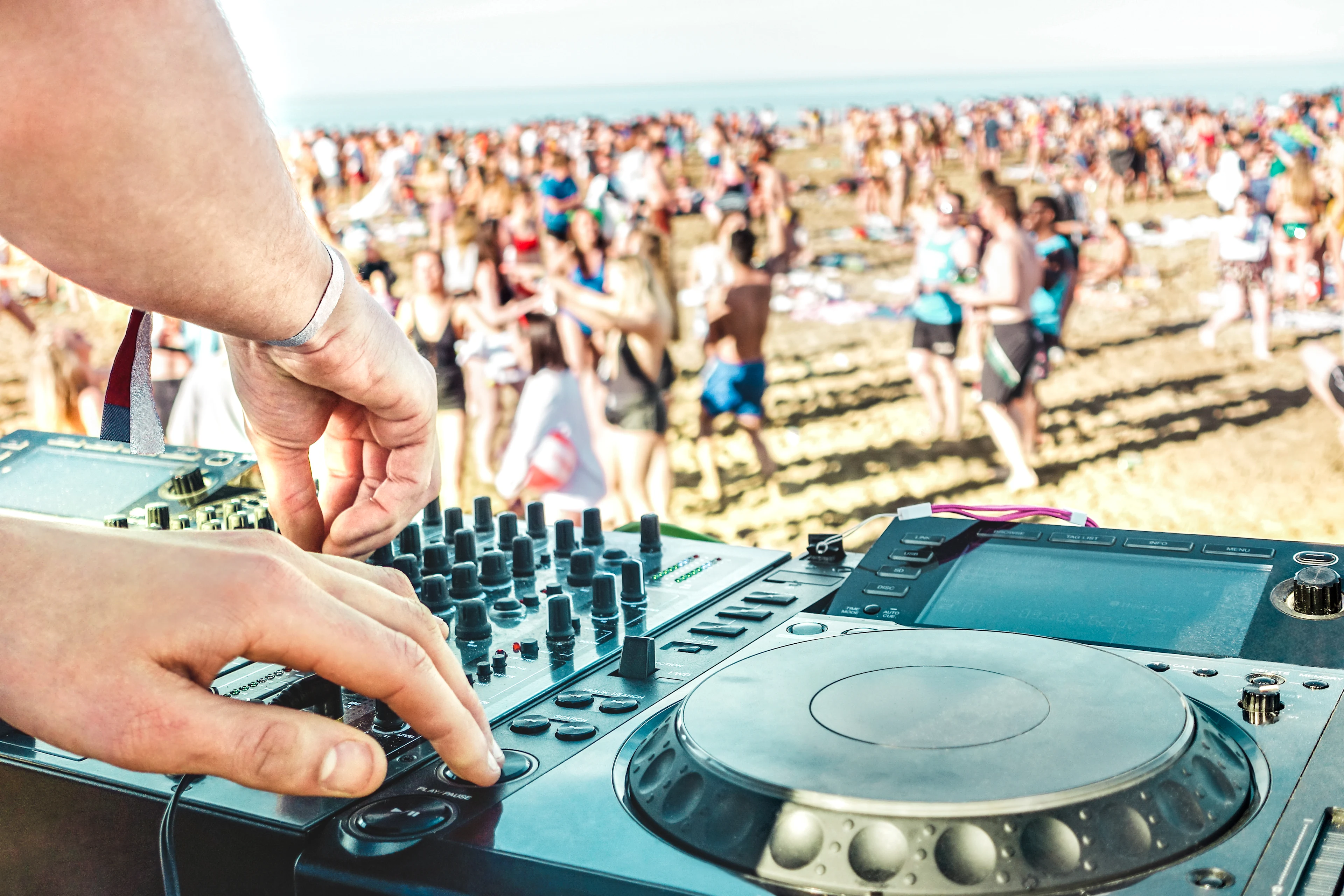 DJ spiller musikk på strandfestival ved havet