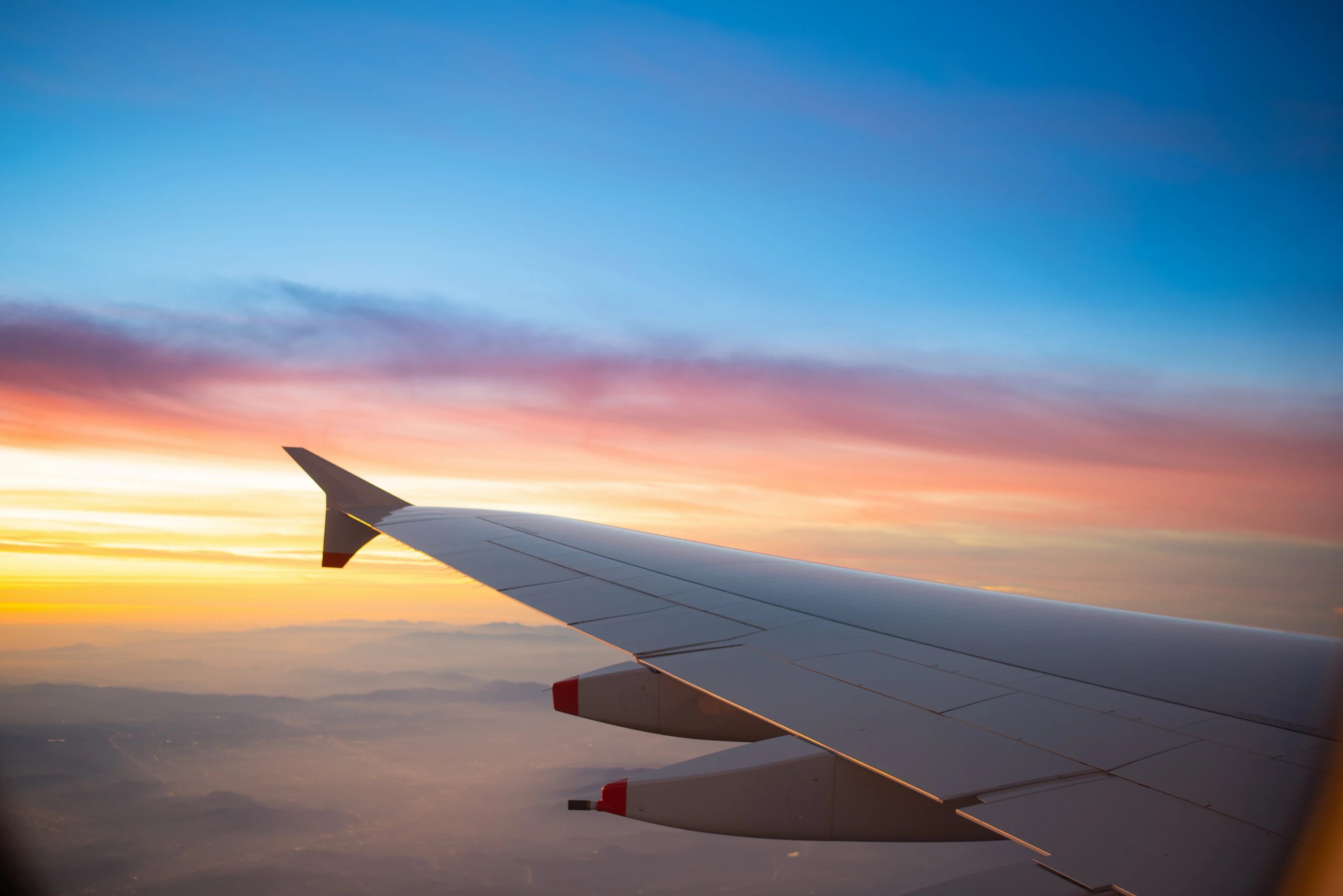 Utsikt fra vindussetet på et fly med solnedgangen i horisonten