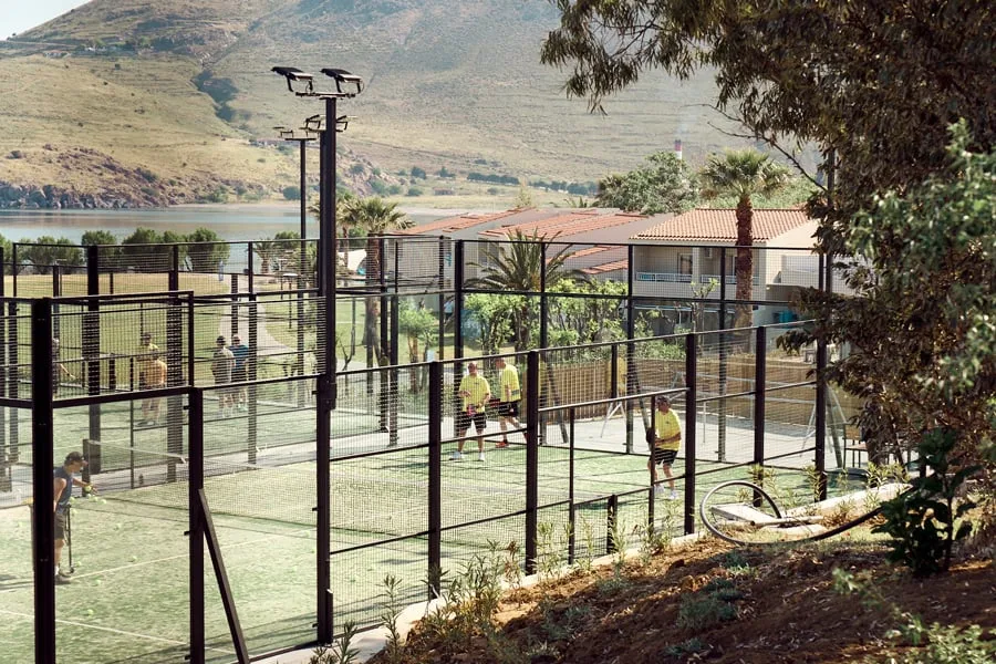 Folk som spiller padel på flere padelbaner med fjell i bakgrunnen