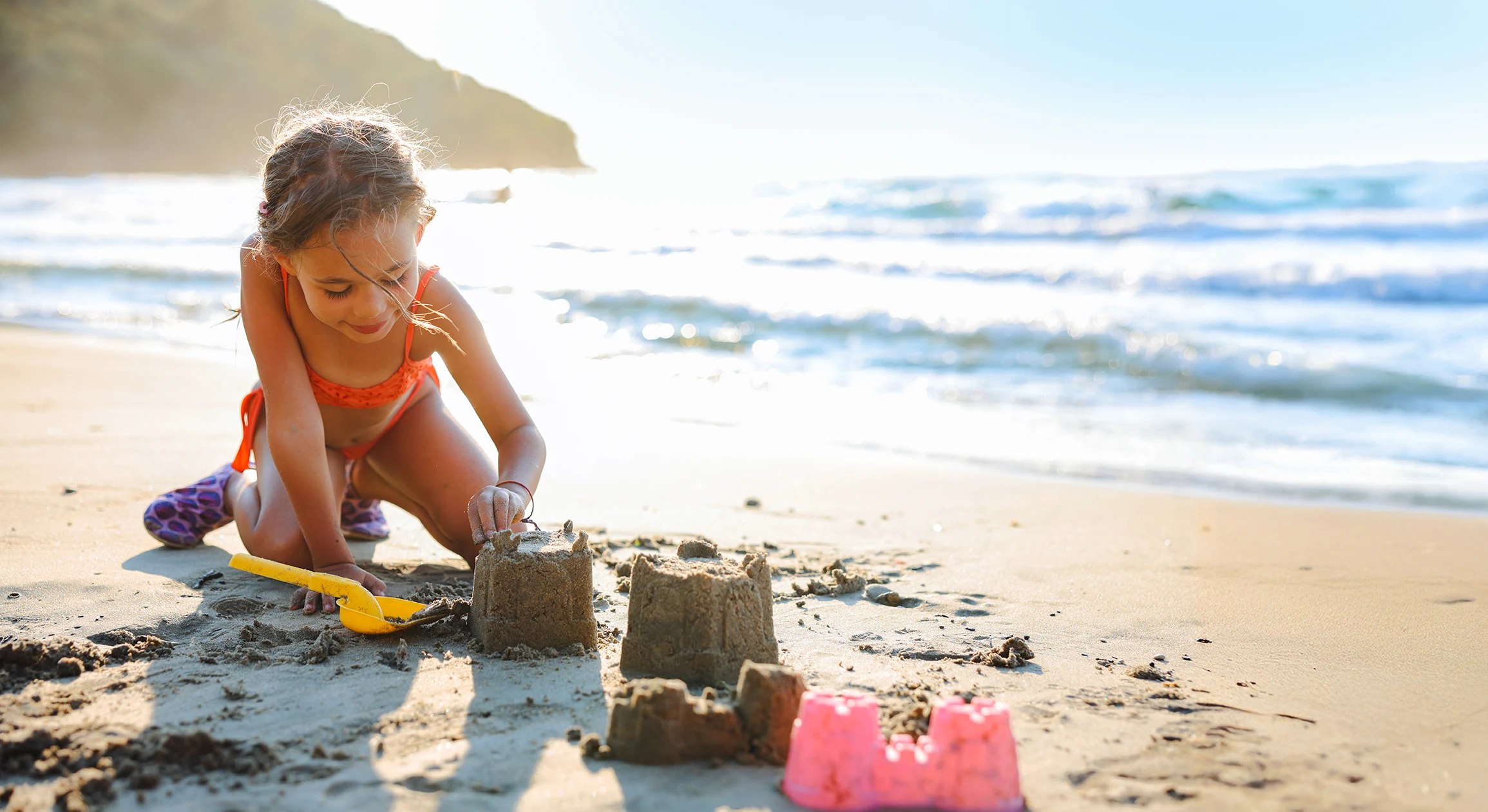 Flicka leker med sand på stranden