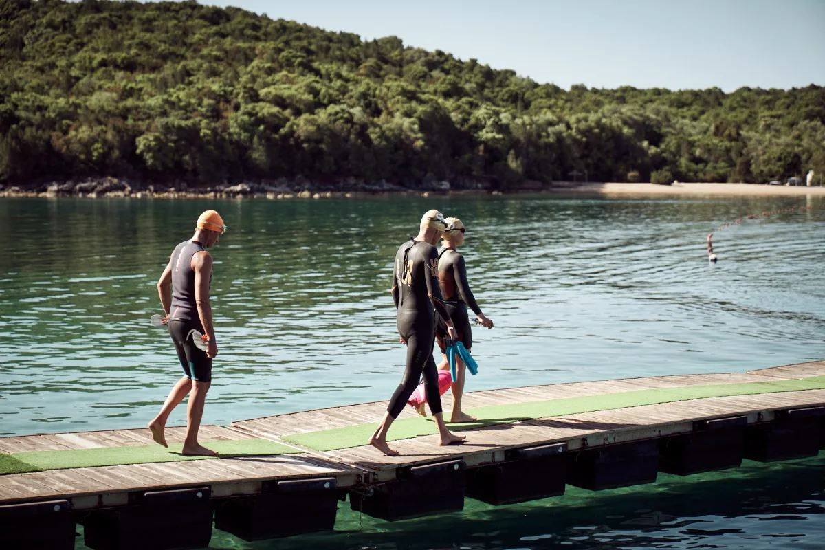 Zwemmers in wetsuits gaan de steiger op