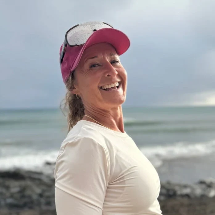 Profilbilde av Ann-Helen Lian ikledd hvit lanermet trøye og rosa caps med beskyttelsesbriller på og havet i bakgrunnen.