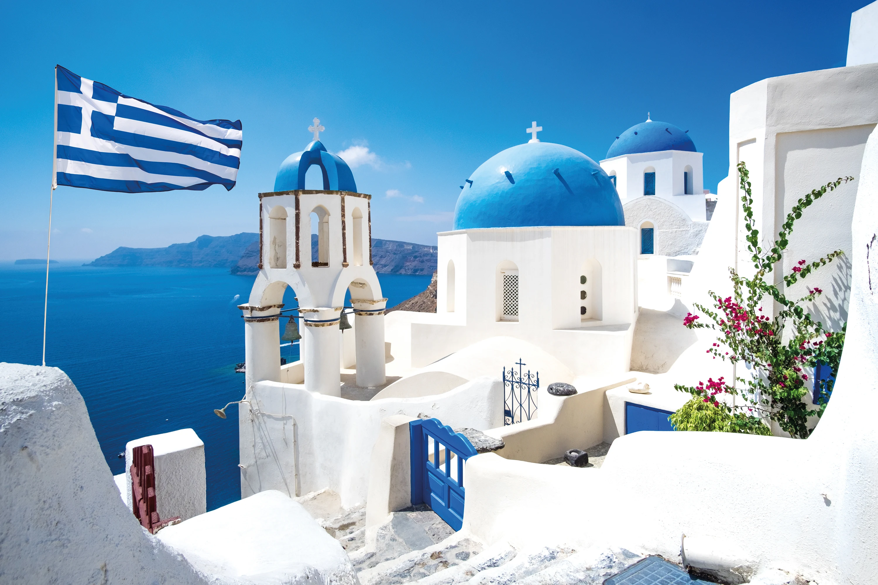 Et bilde fra flotte Santorini med hvitkalkede hus og kirker. Det greske flagget vaier i vinden