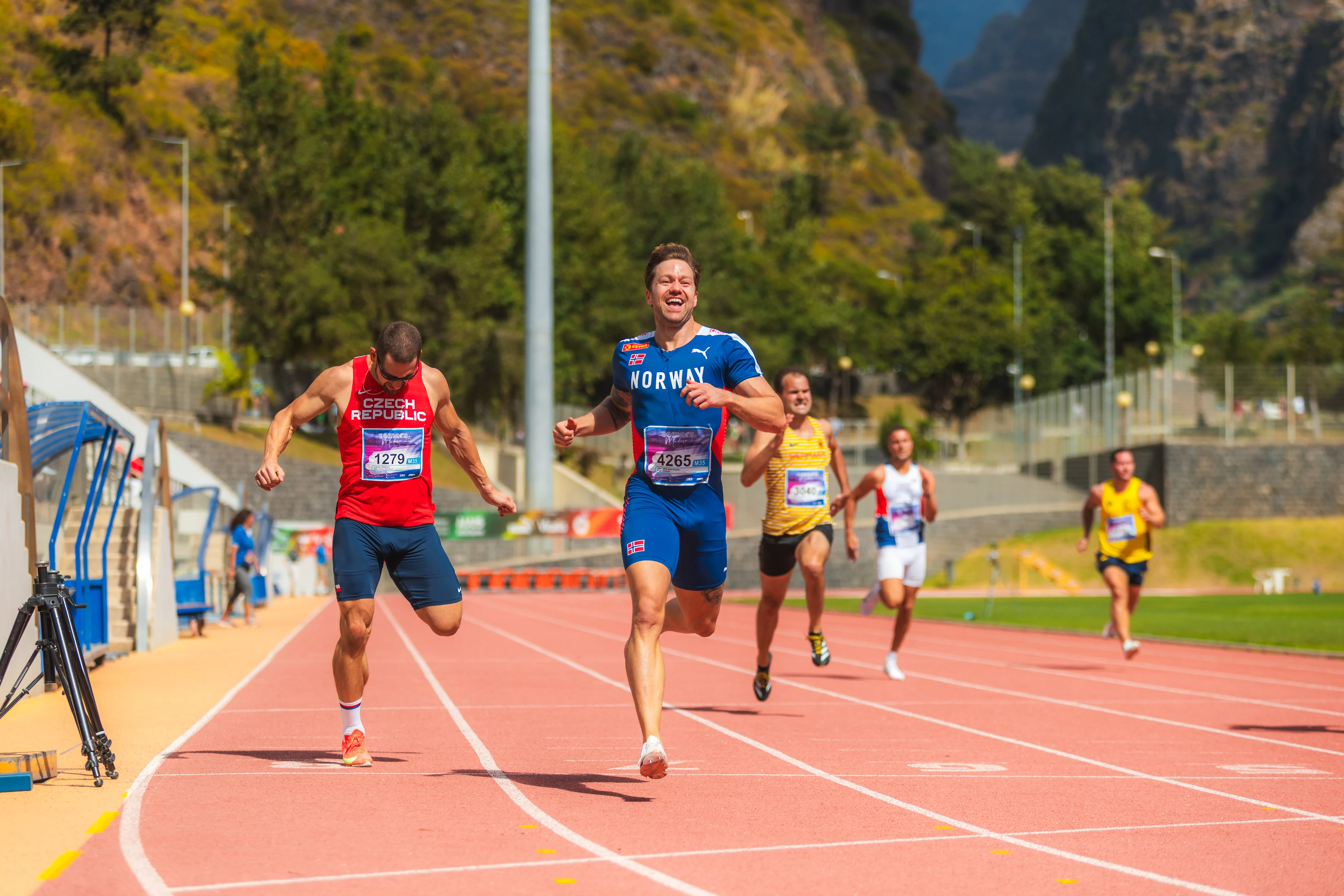 Hallgeir som løper på bane i blått med konkurrenter i bakgrunnen.