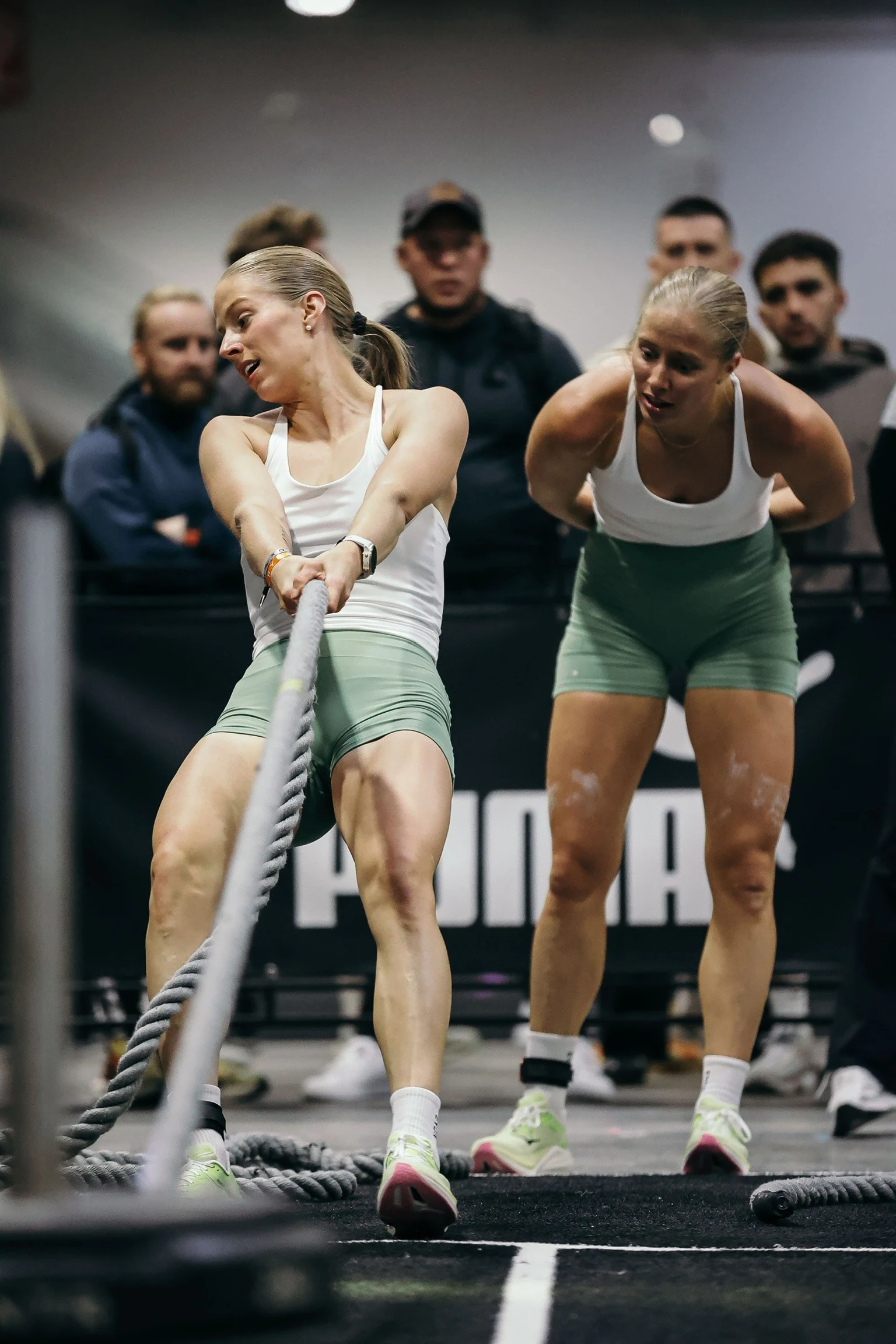 Guro og Elin kledd i hvite treningstopper og lys grønne treningsshorts. Elin heier på mens Guro trekker i et tau.