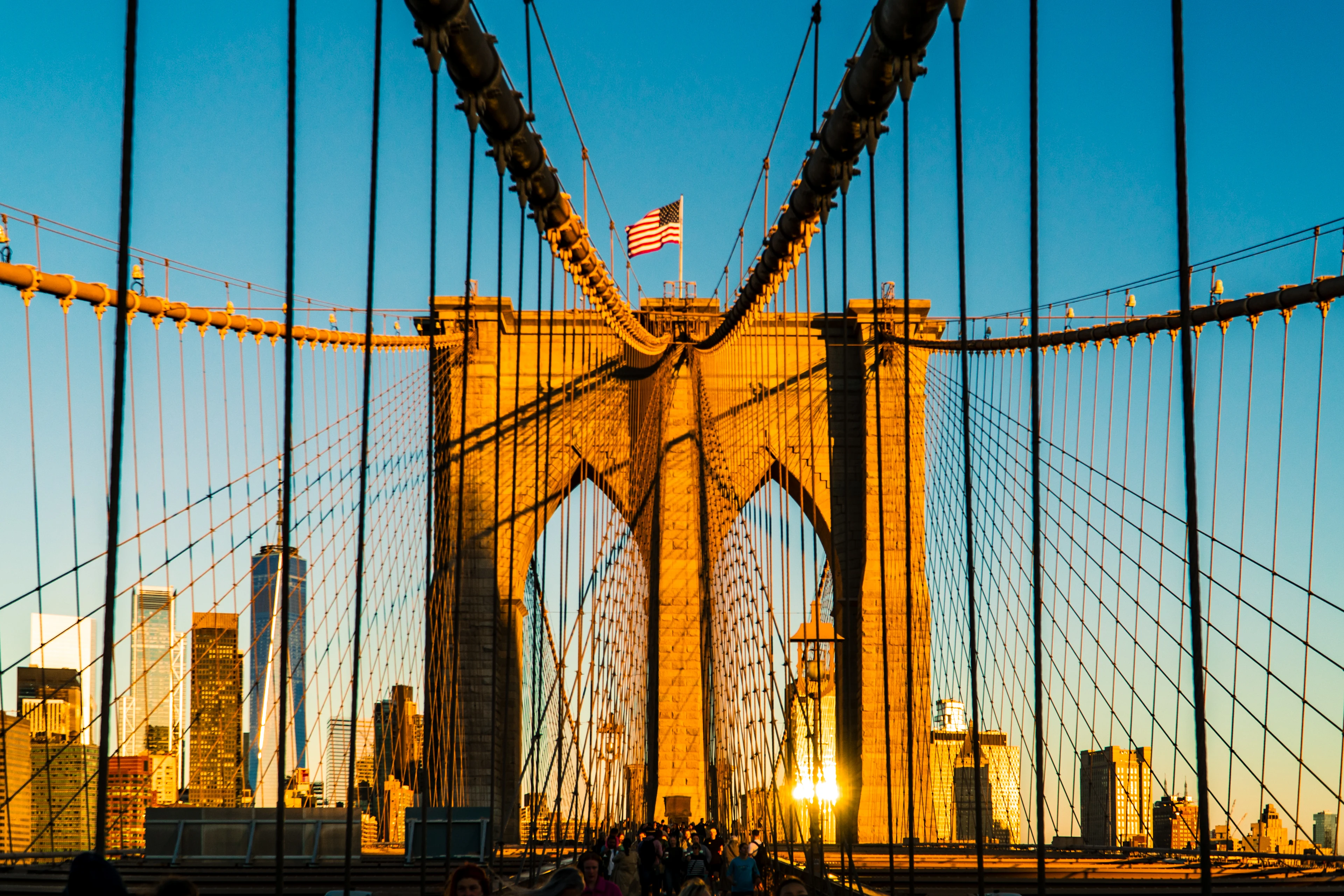 Brooklyn Bridge i New York med Manhattans skyline i bakgrunnen ved solnedgang.
