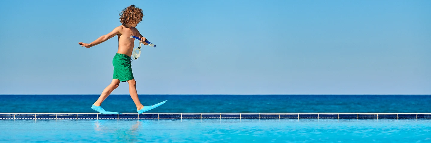 Pojke går på poolkant med simfötter