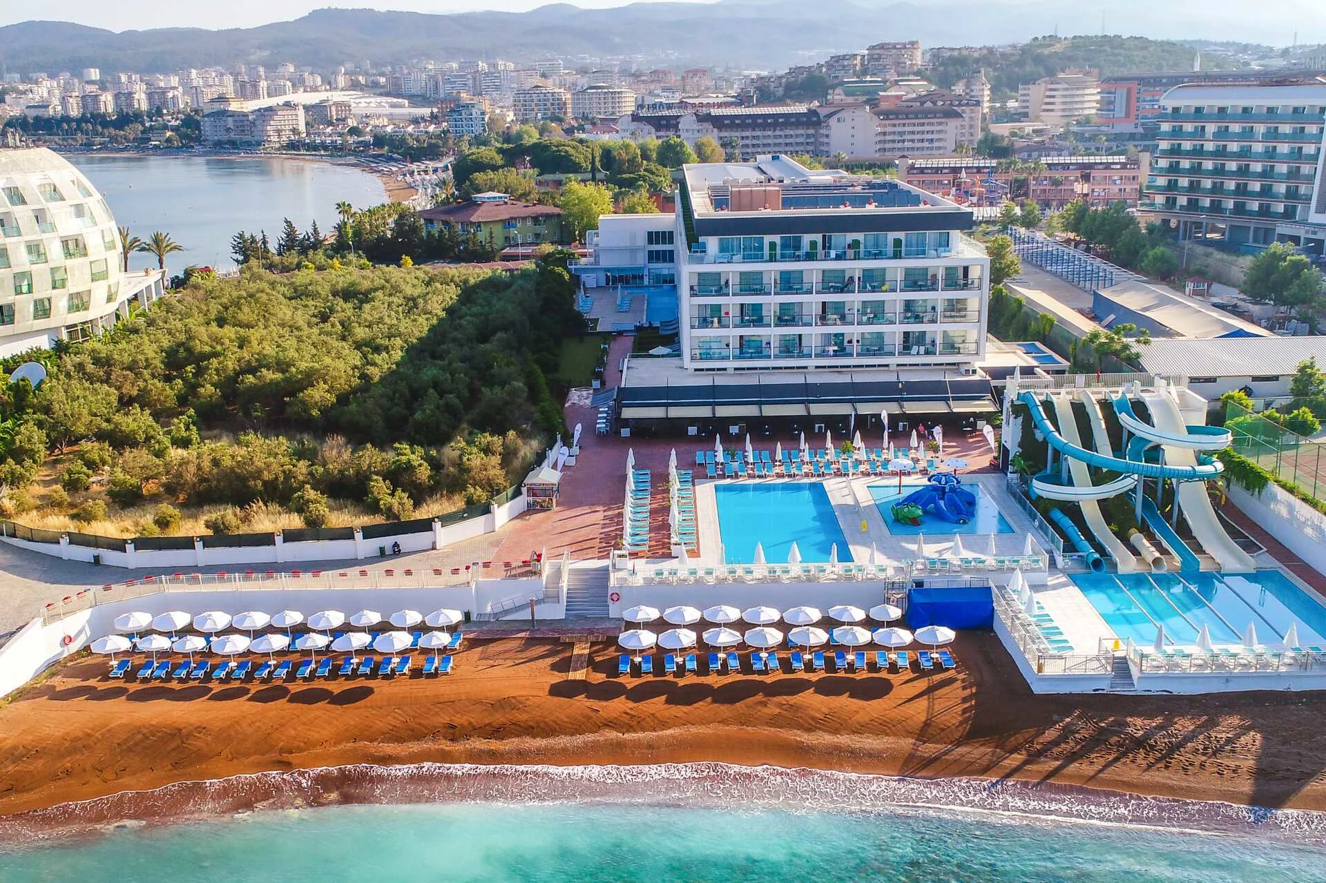 Hotell i Alanya vid stranden med poolområde, solstolar och vattenrutschkanor vid Turkiets kust. Hotellet heter Lonicera West.