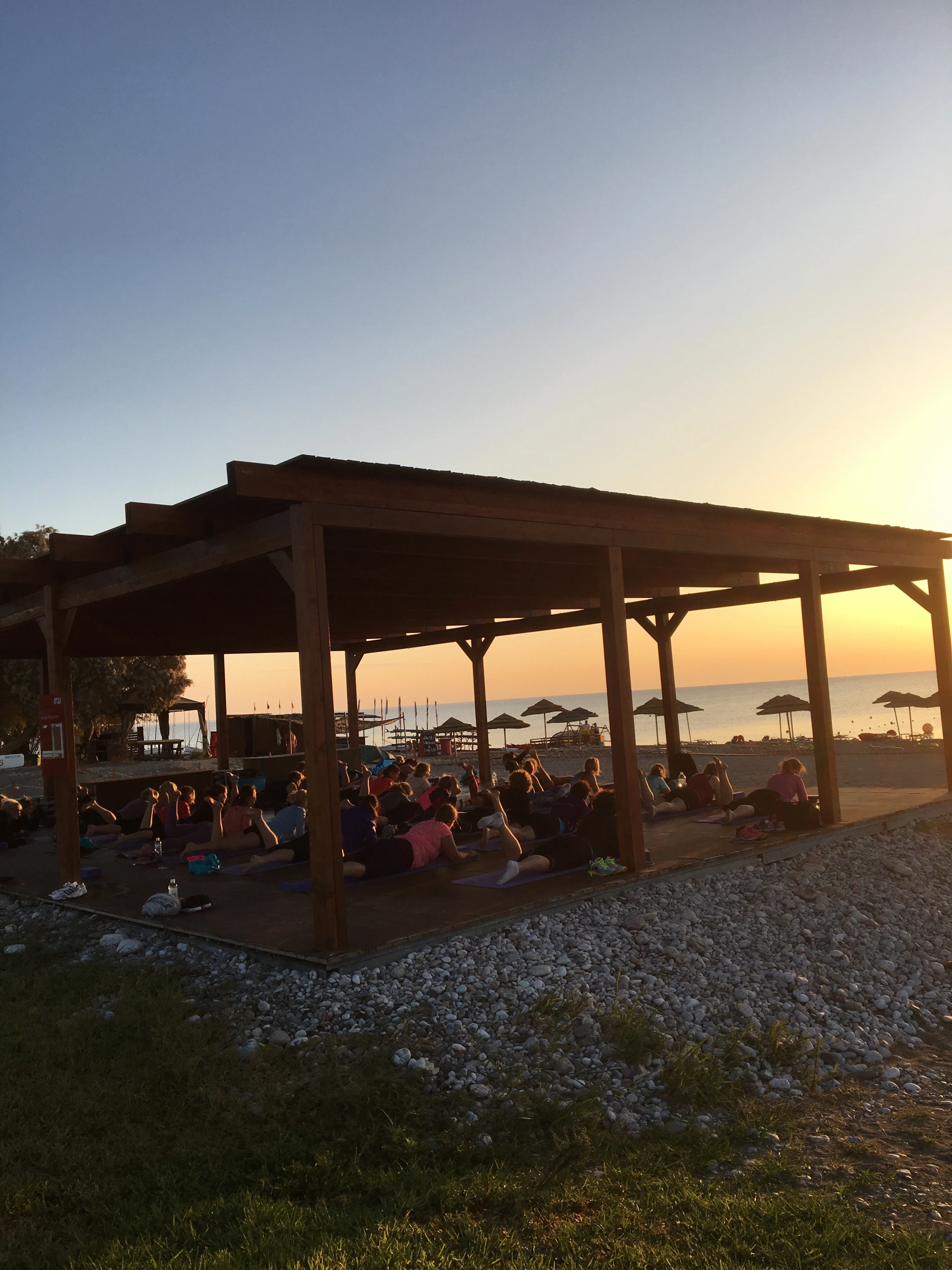 Treningsplattform på stranden ved Levante – powered by Playitas og deltagere som gjør morgen yoga.