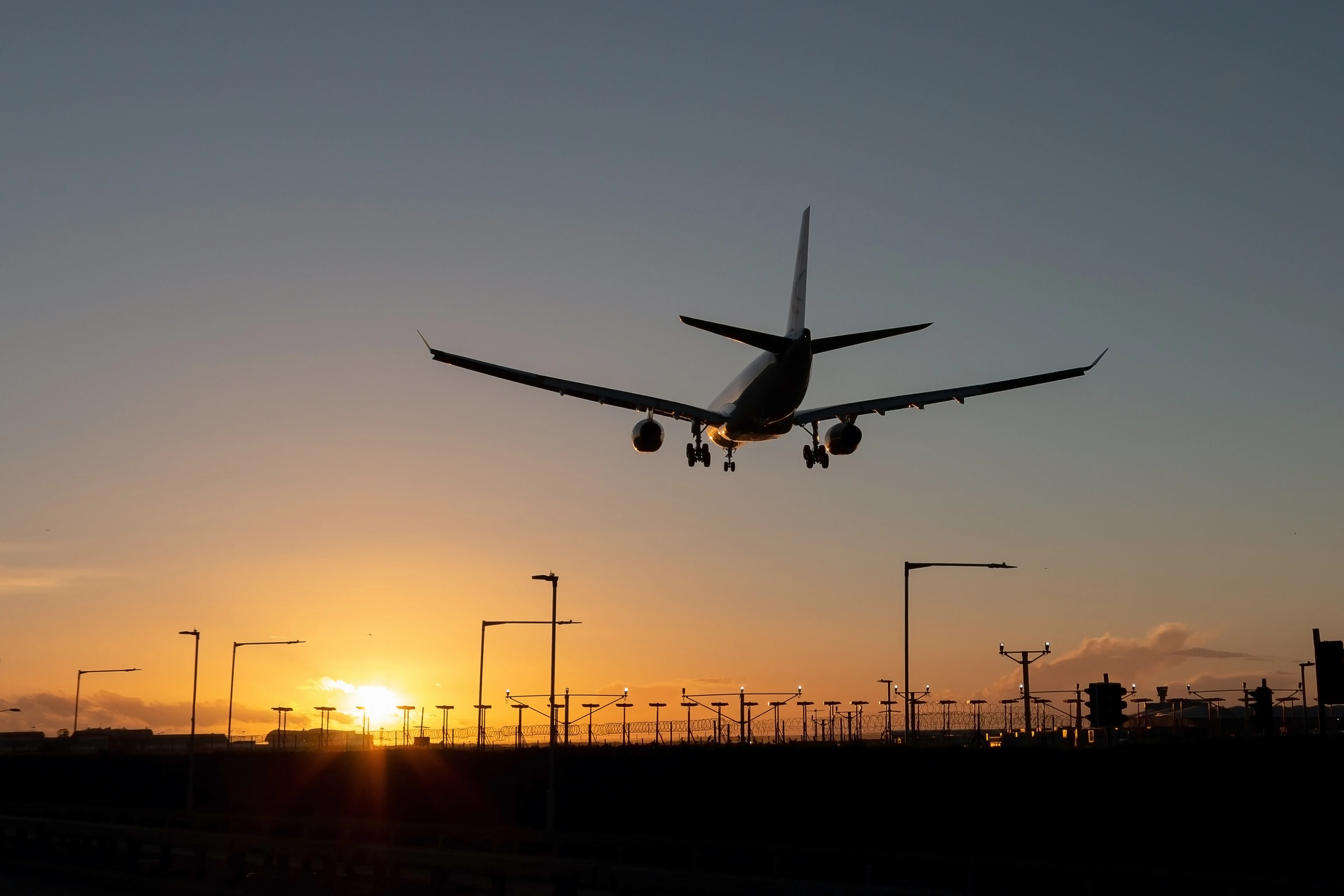 Flygplan på väg att landa på flygplats i solnedgången