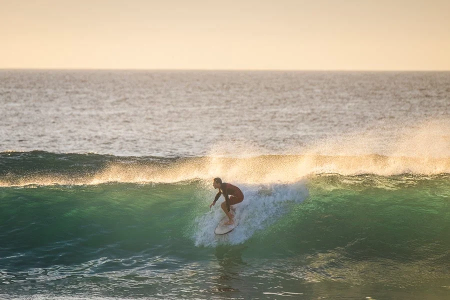 Surfer på en stor bølge i solnedgang