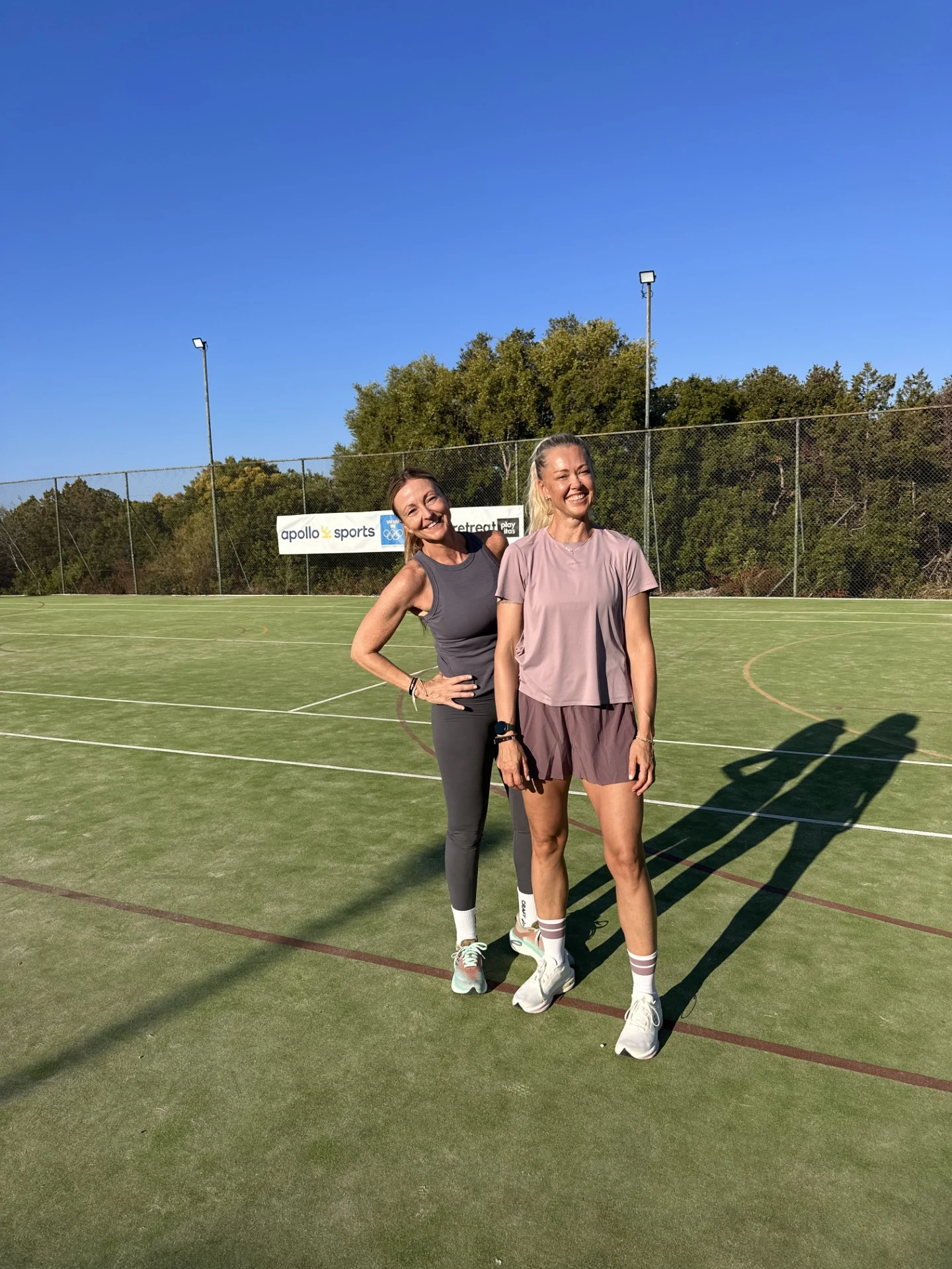 Tove og Cathrine står ute på en idrettsbane ikledd treningstøy.