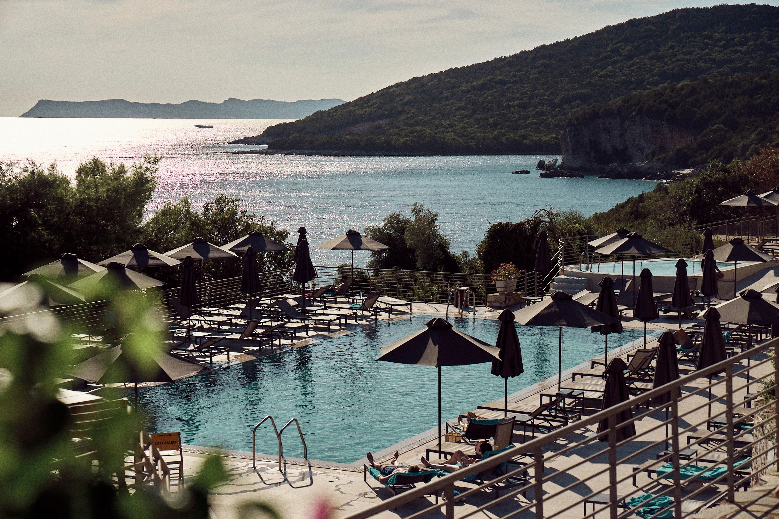 Oversikt over bassenget på Sivota Retreat med havet i bakgrunnen. 