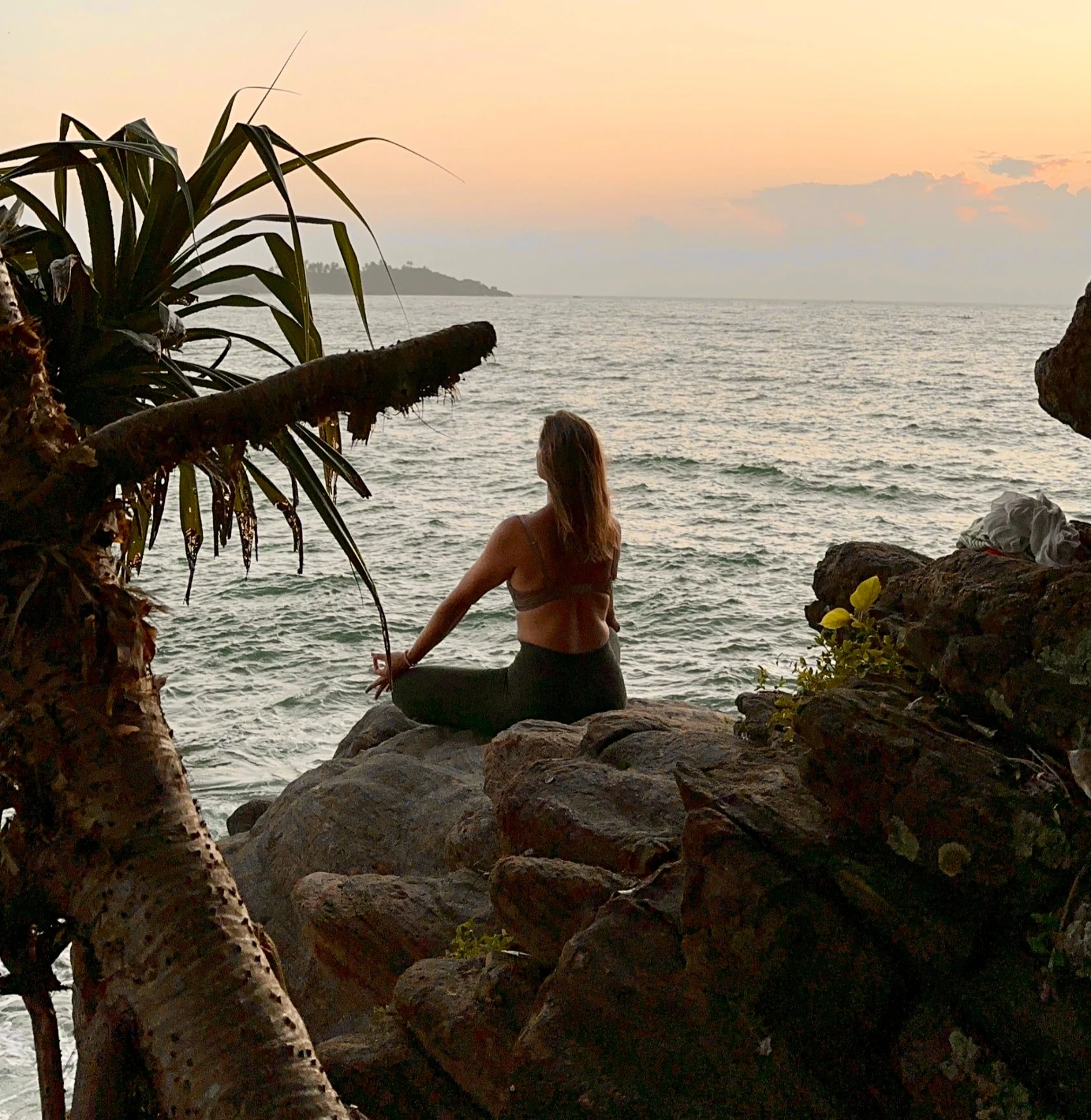 Cecilie H. Eggen som sitter med ryggen til på en fjellhylle og ser ut over havet.