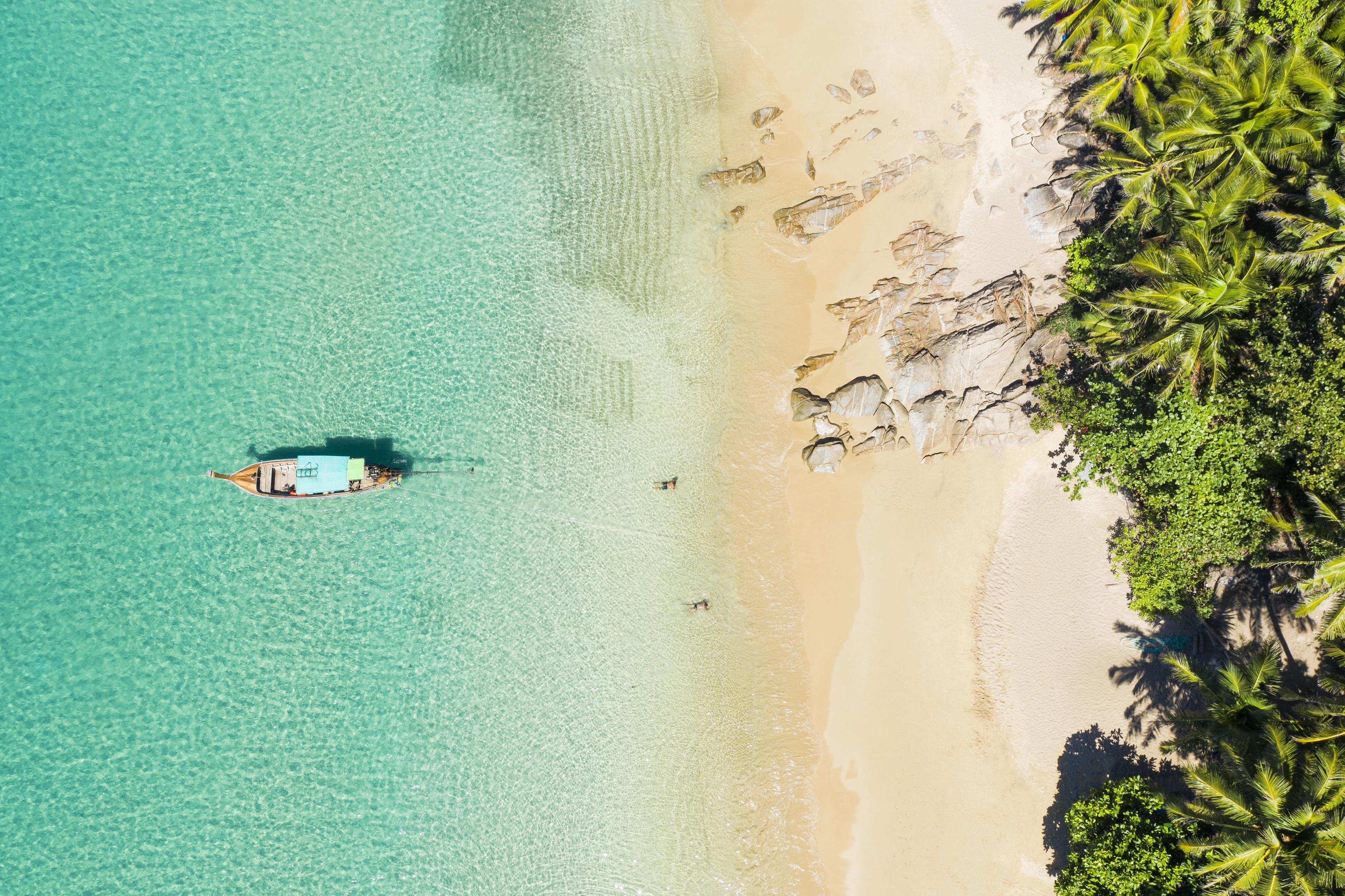 Dronebilde av en vakker hvit sandstrand med turkist vann og palmer