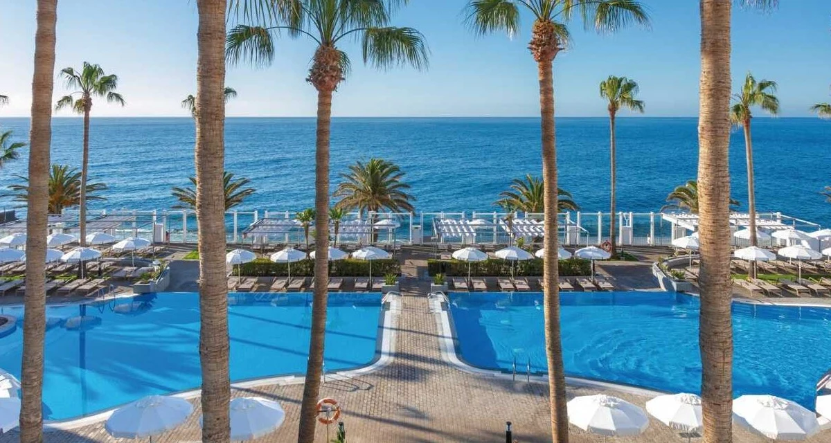 Utsikt över palmer, pool och hav på hotell Riu Madeira
