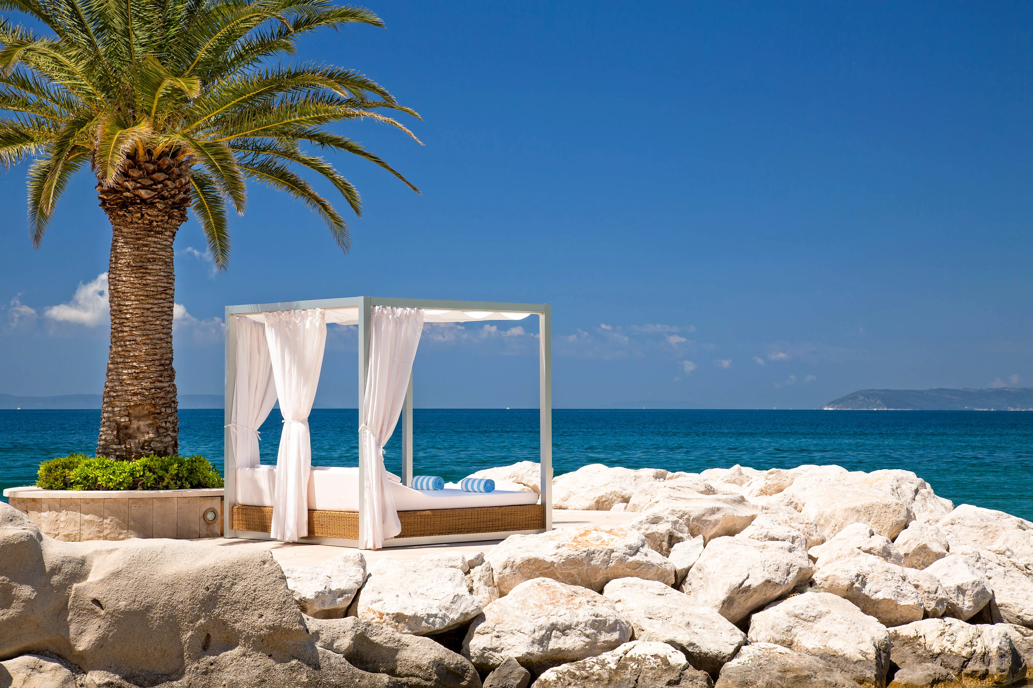 Palm, strandcabana och turkost hav vid kusten i Podstrana utanför Split.