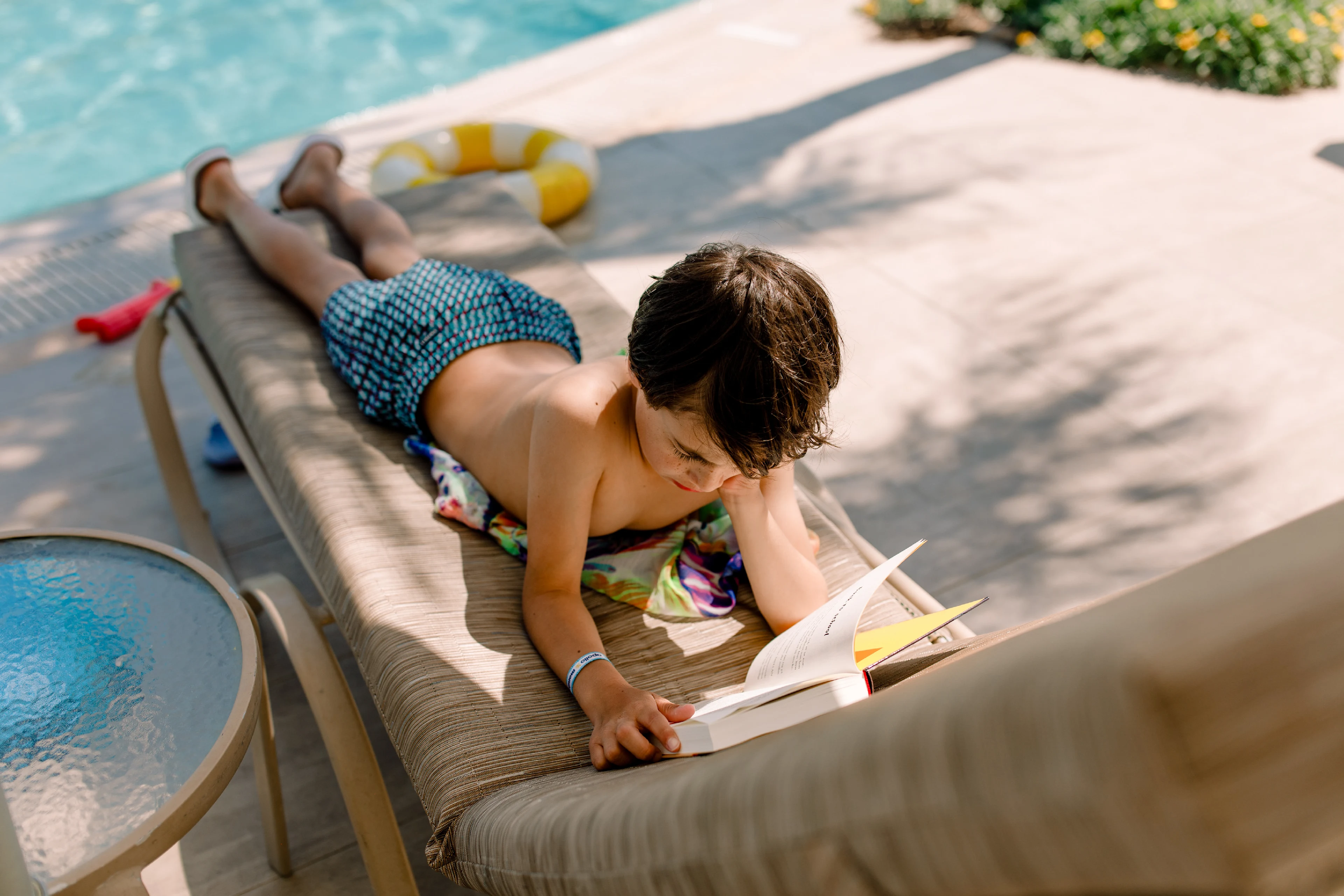 Jongen ligt te lezen in de ligstoel van het Mythos Beach hotel