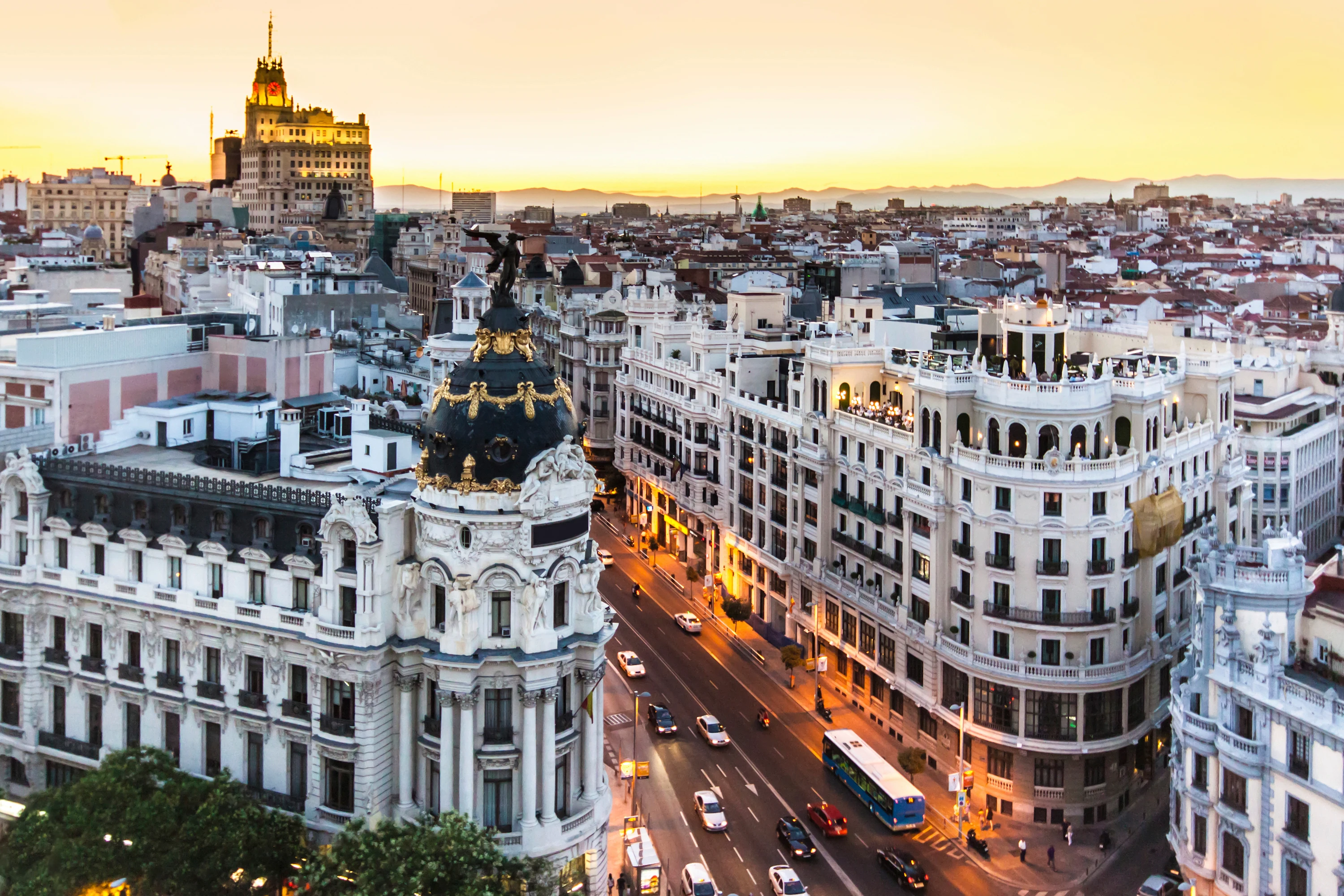 Udsigt over Gran Vía i Madrid med Metropolis-bygningen i forgrunden og byens historiske arkitektur i skumringen.