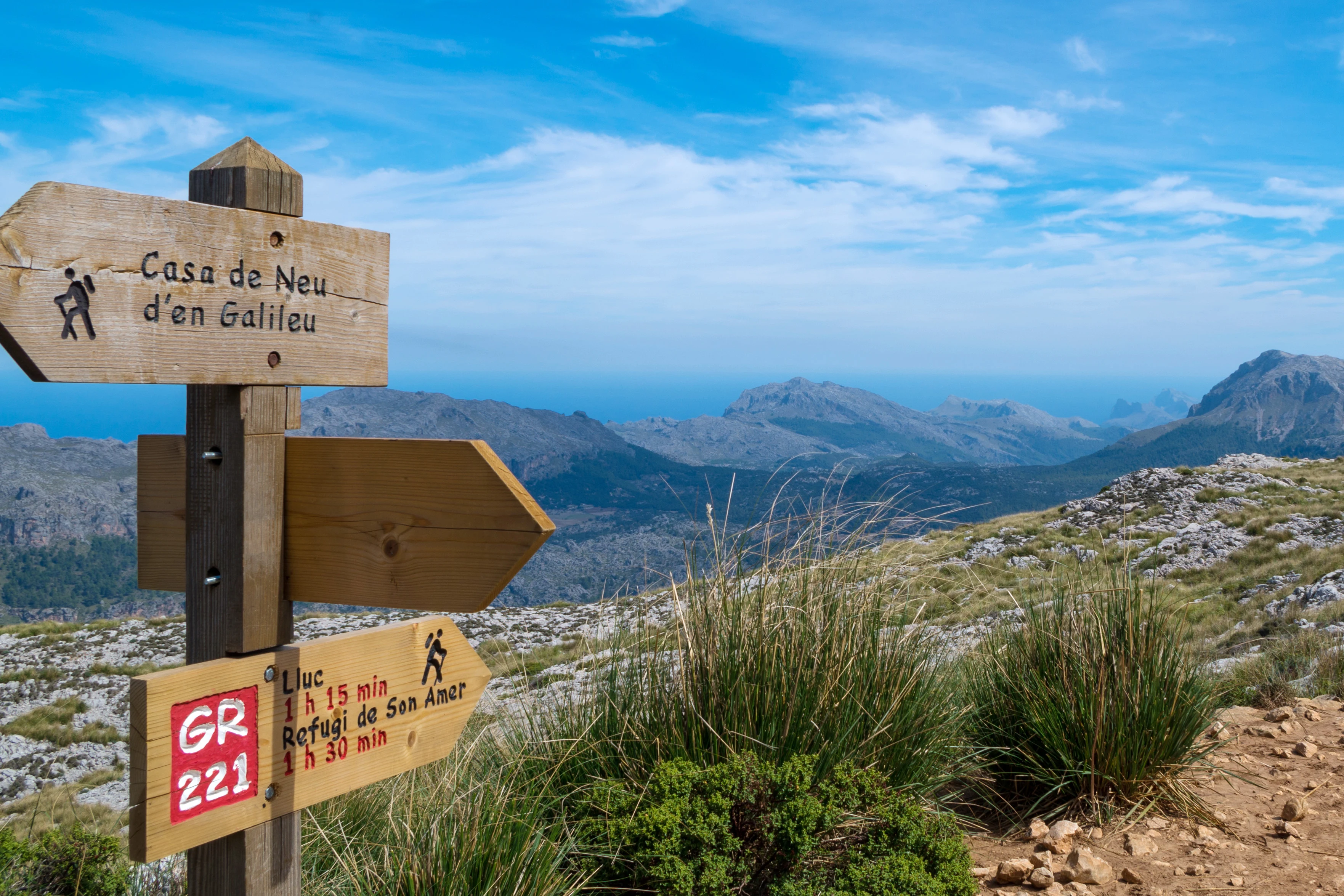 En skylt i trä som visar vägen till olika vandringar uppe i bergen på Mallorca
