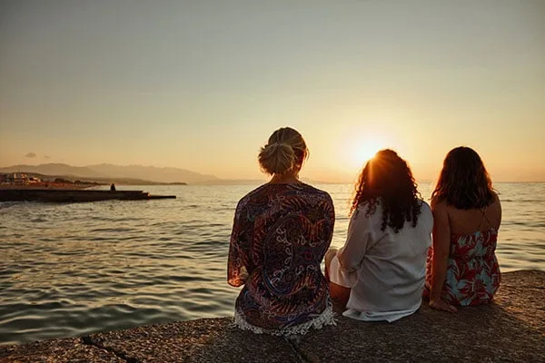 Drie mensen zitten en kijken naar de zonsondergang