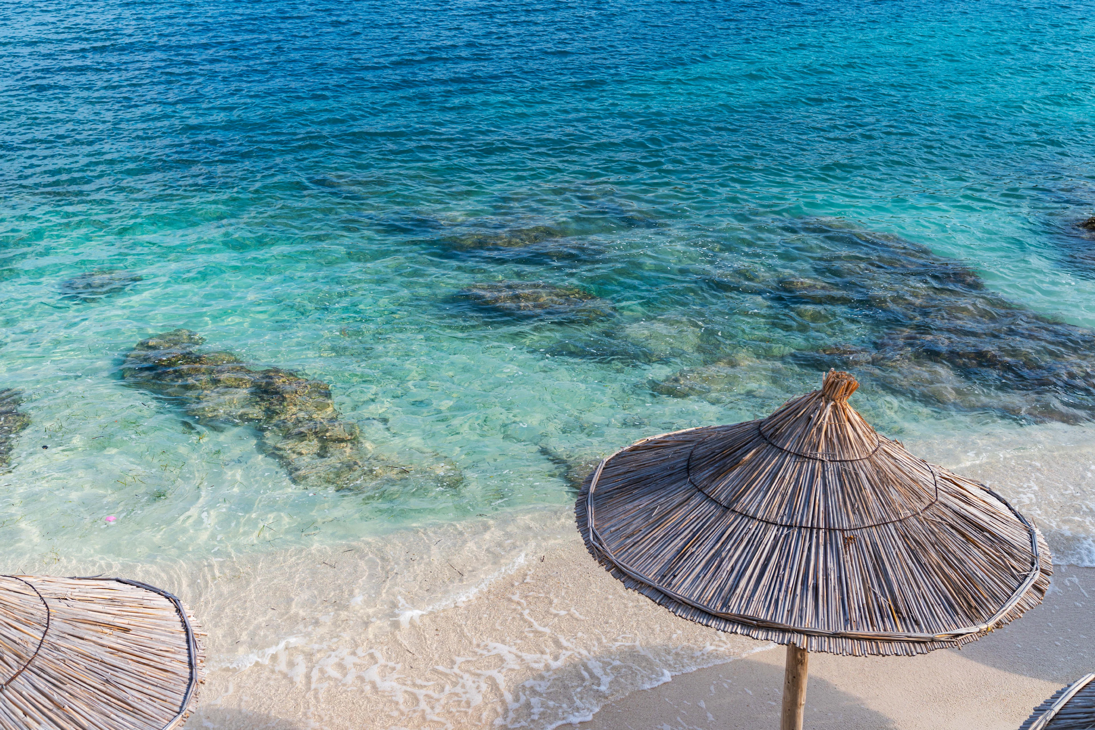 Parasol op een strand met kristalhelder water in Albanië