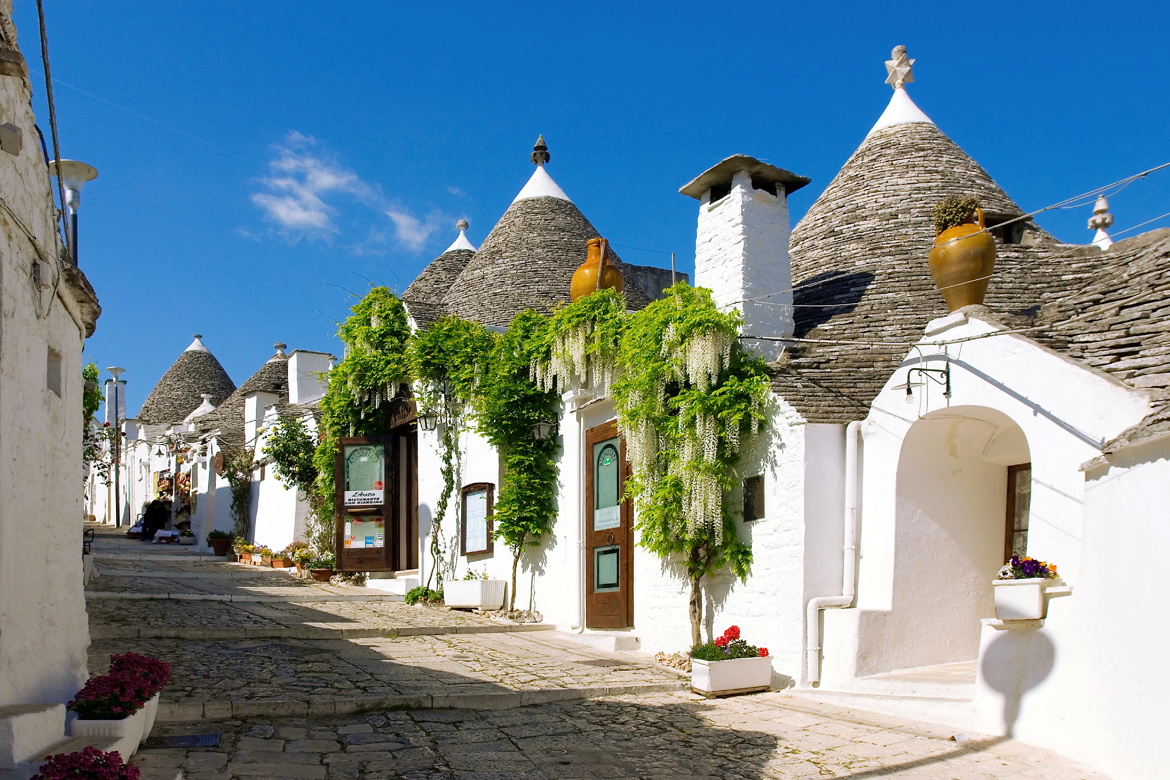 Brostensbelagt gade mellem de hvidkalkede trulli-huse
