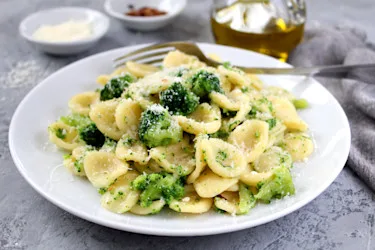 En hvit tallerken med orecchiette-pasta med brokkoli, toppet med revet parmesan