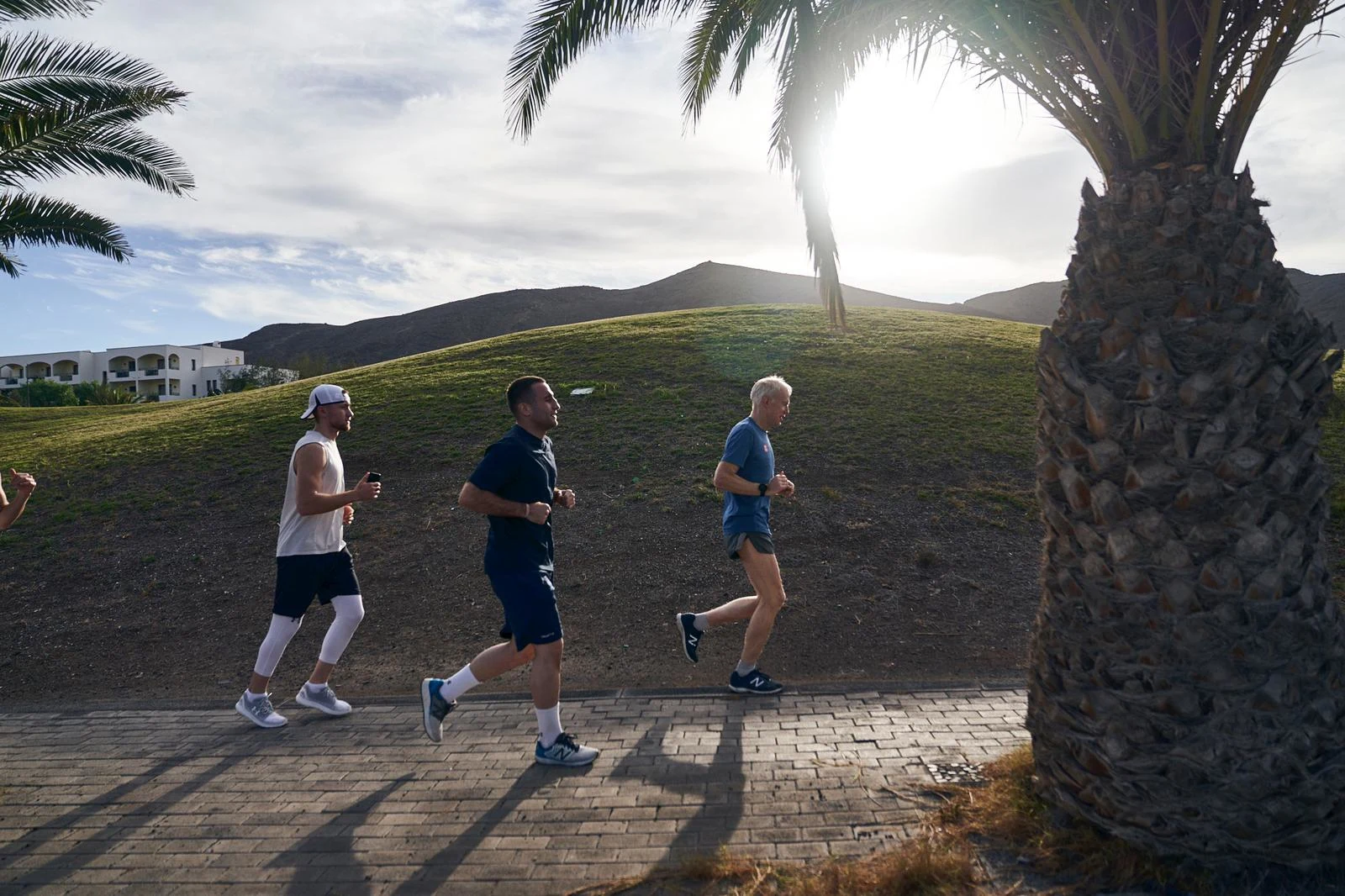 Tre menn som løper inne på Playitas' område i soloppgang
