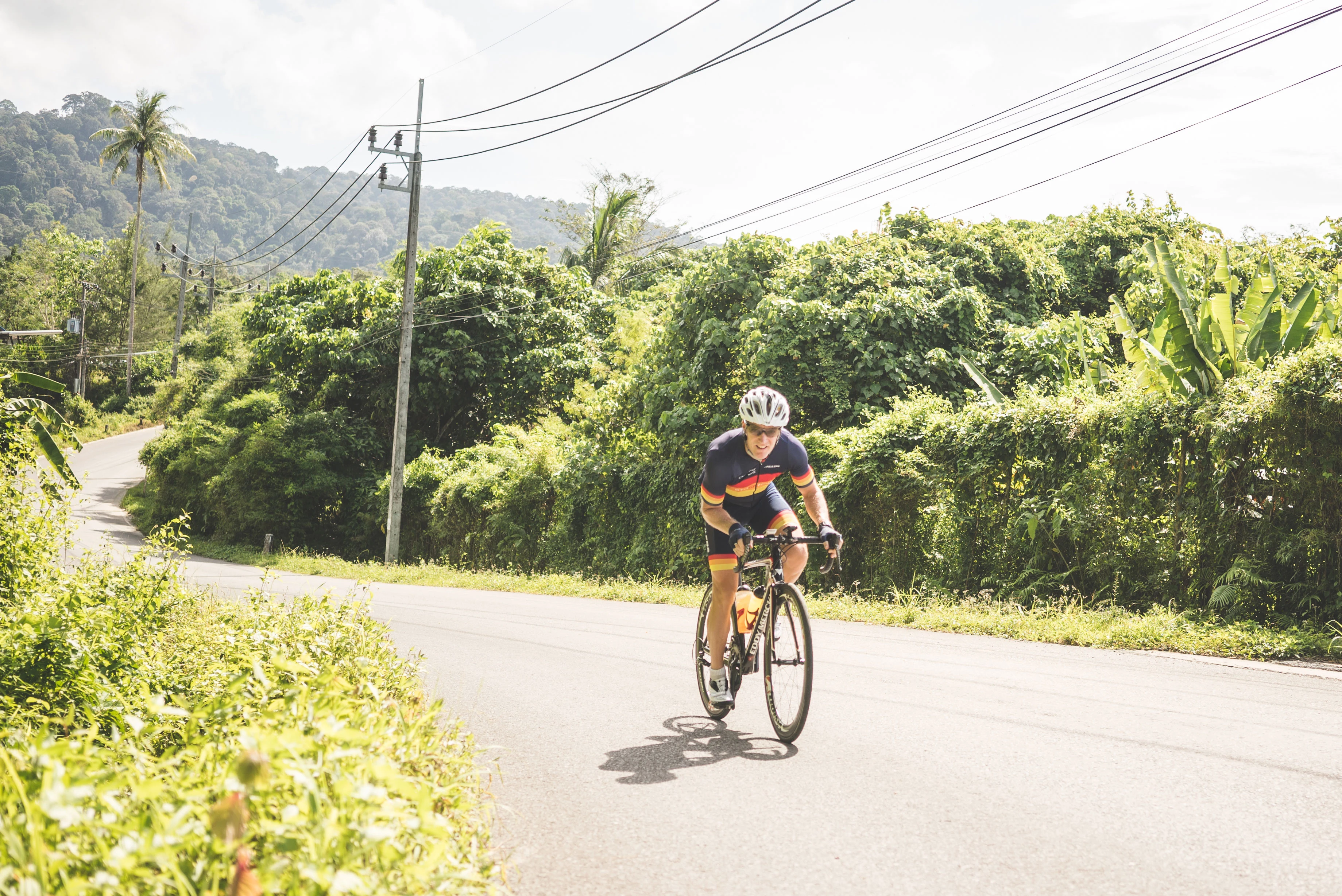 En mand, der cykler langs en vej i Krabi med frodige palmer i baggrunden
