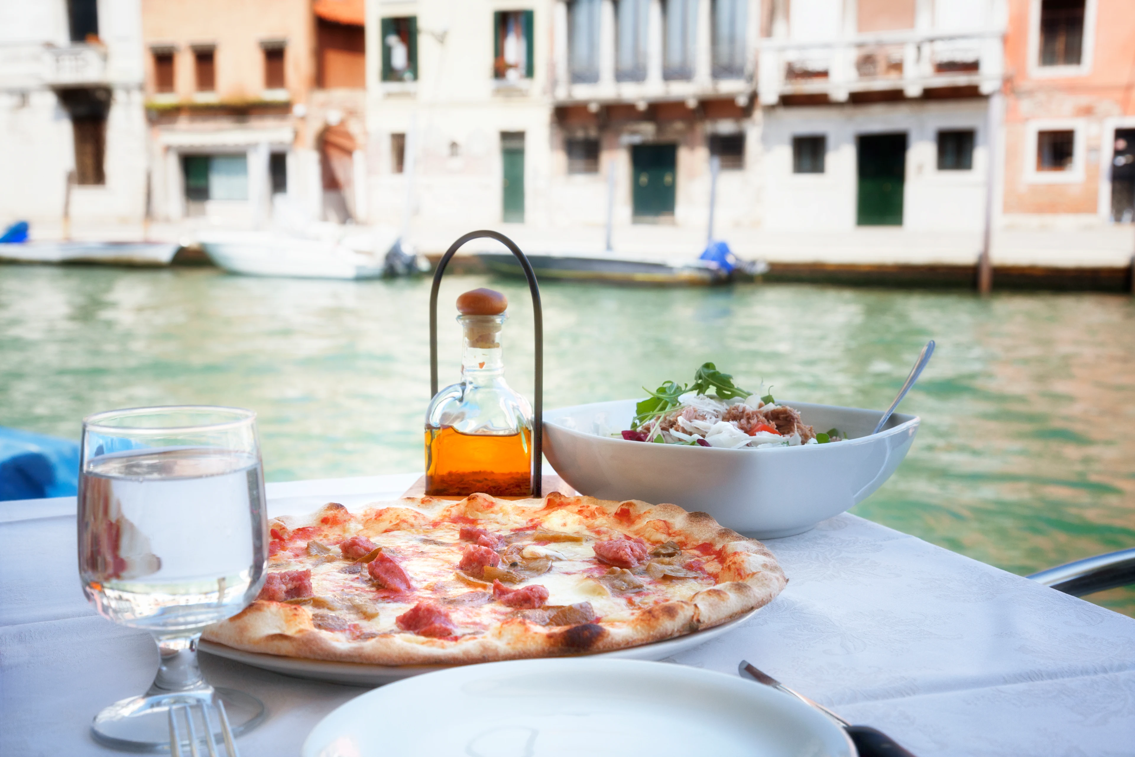 Pizzaa ja salaattia tarjoiltuna kanavan rannalla Venetsiassa