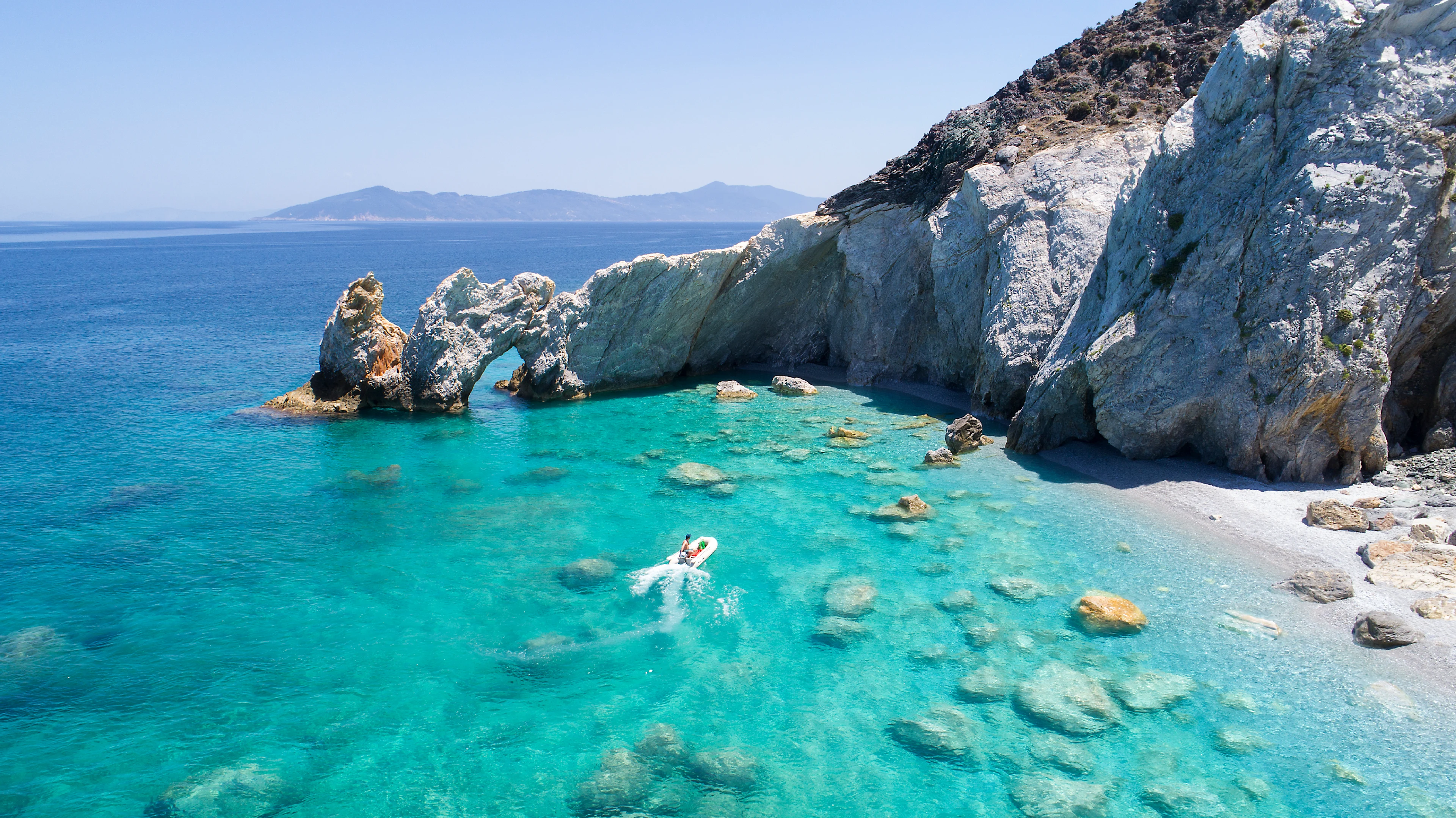 En liten båt på väg mot en strand på Skiathos