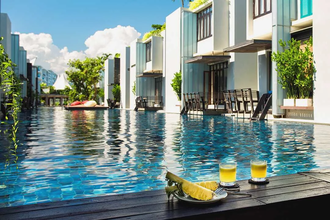 Pool och hotellområde på resorten Let´s sea Huia Hin i Thailand. Intill poolen ligger det uppdukat två drinkar och en delad annans 