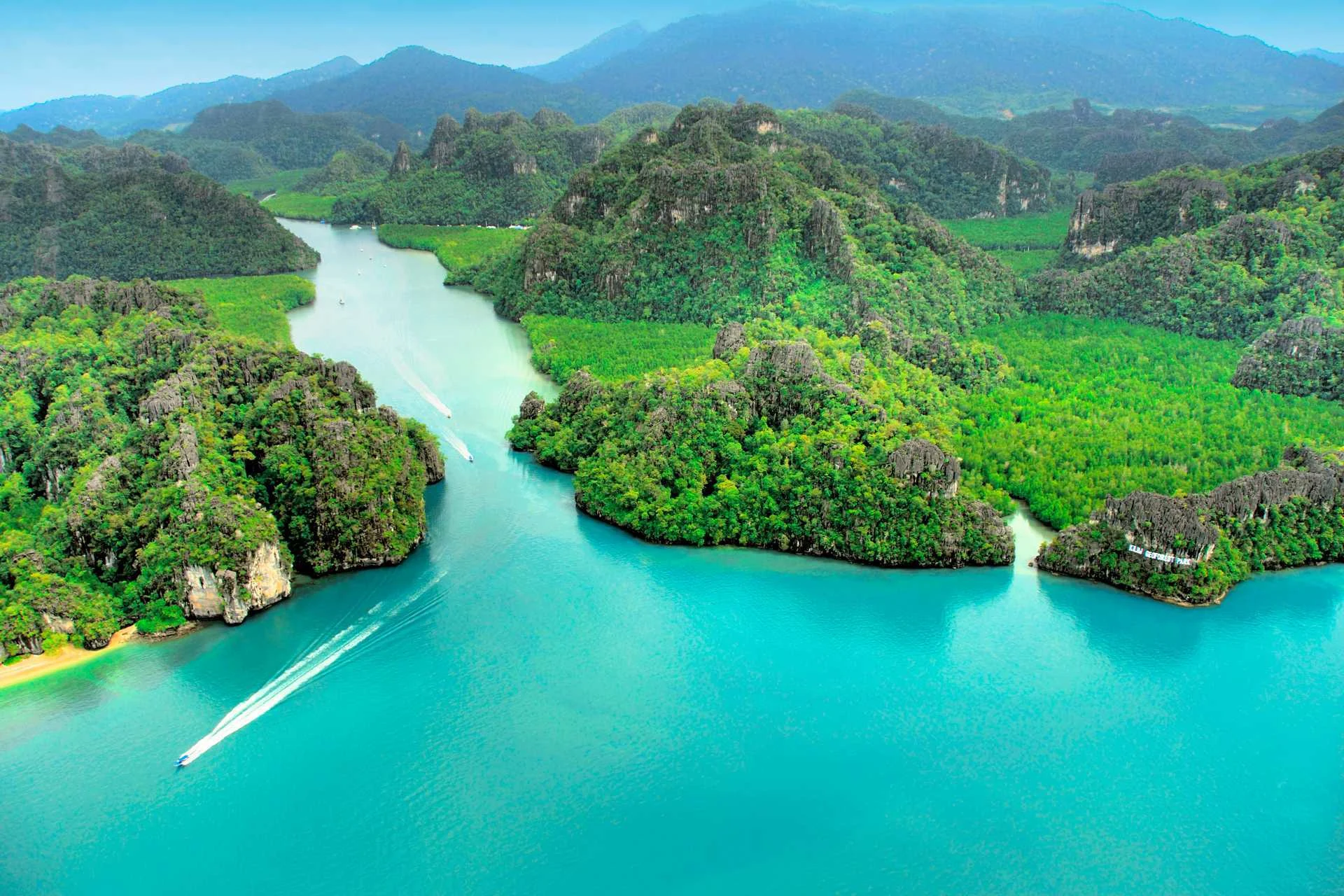 Både dukker op fra en turkis fjord omgivet af frodig regnskov på Langkawi.