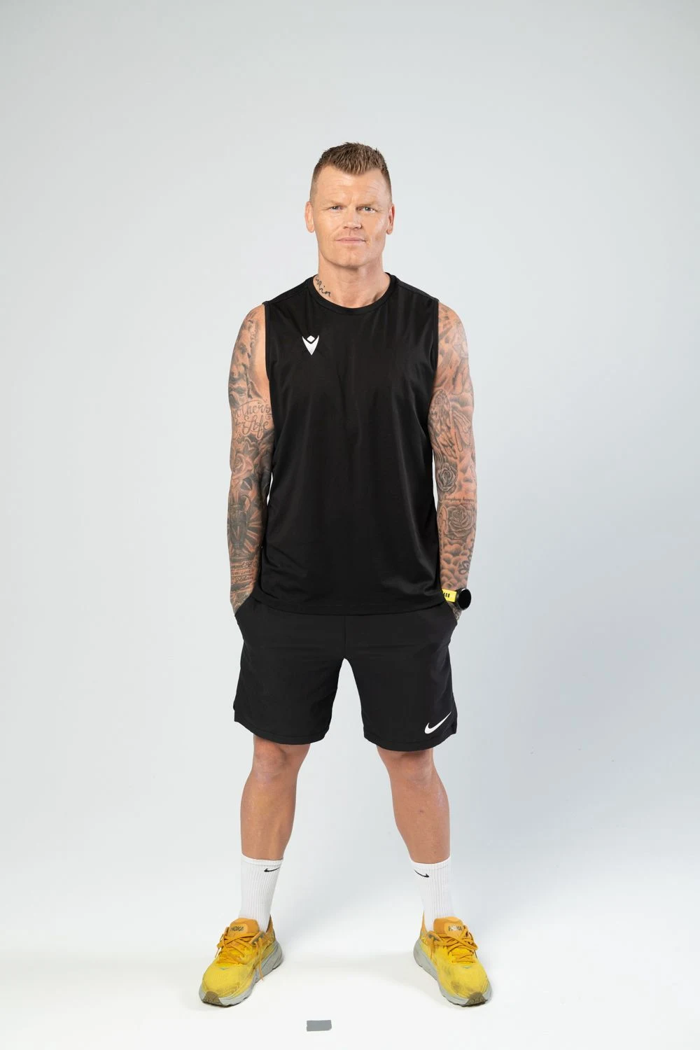 John Arne Riise som står i svart topp og shorts og gule joggesko.