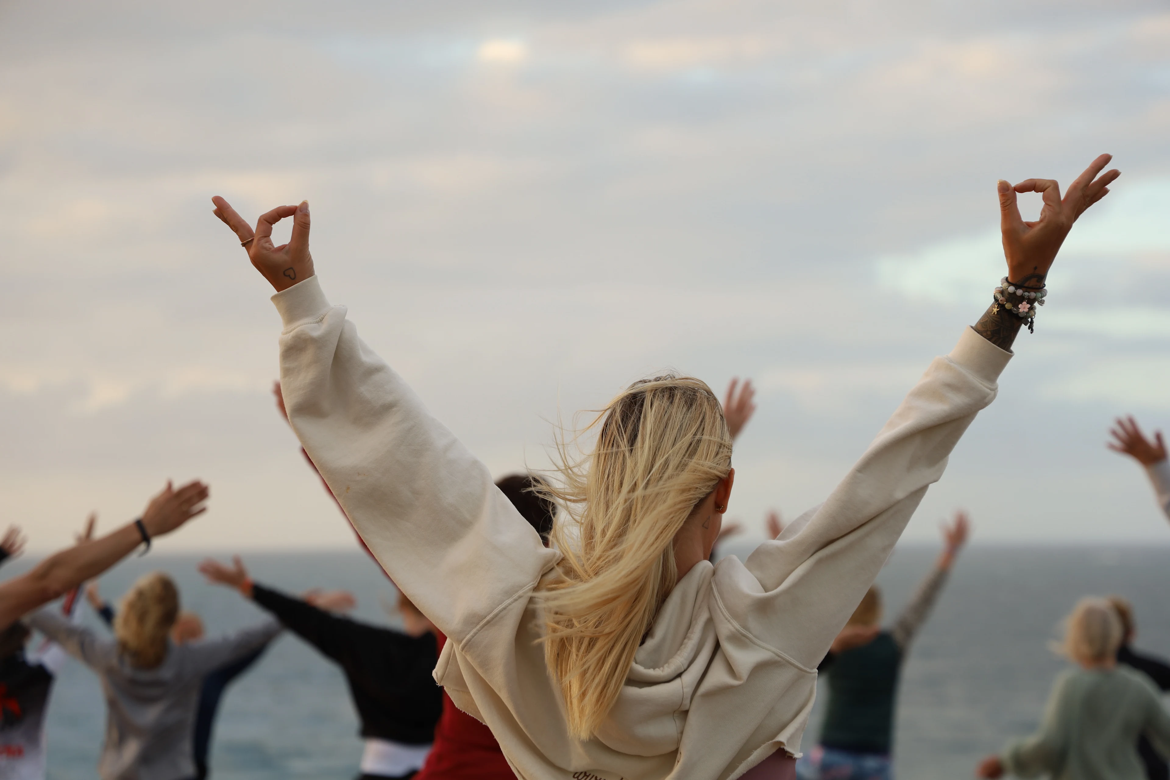  Personer deltar i meditation utomhus med havet i bakgrunden