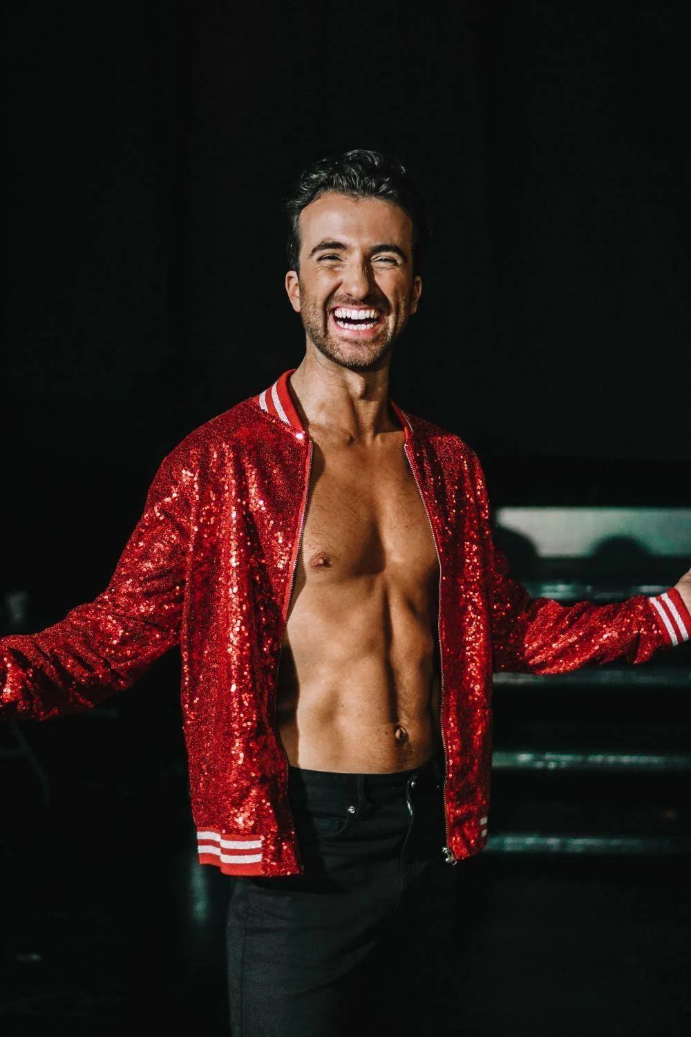 Danseren Santino Mirenna står vendt mot kamerat i en rød glitterjakke som er åpen med armene ut
