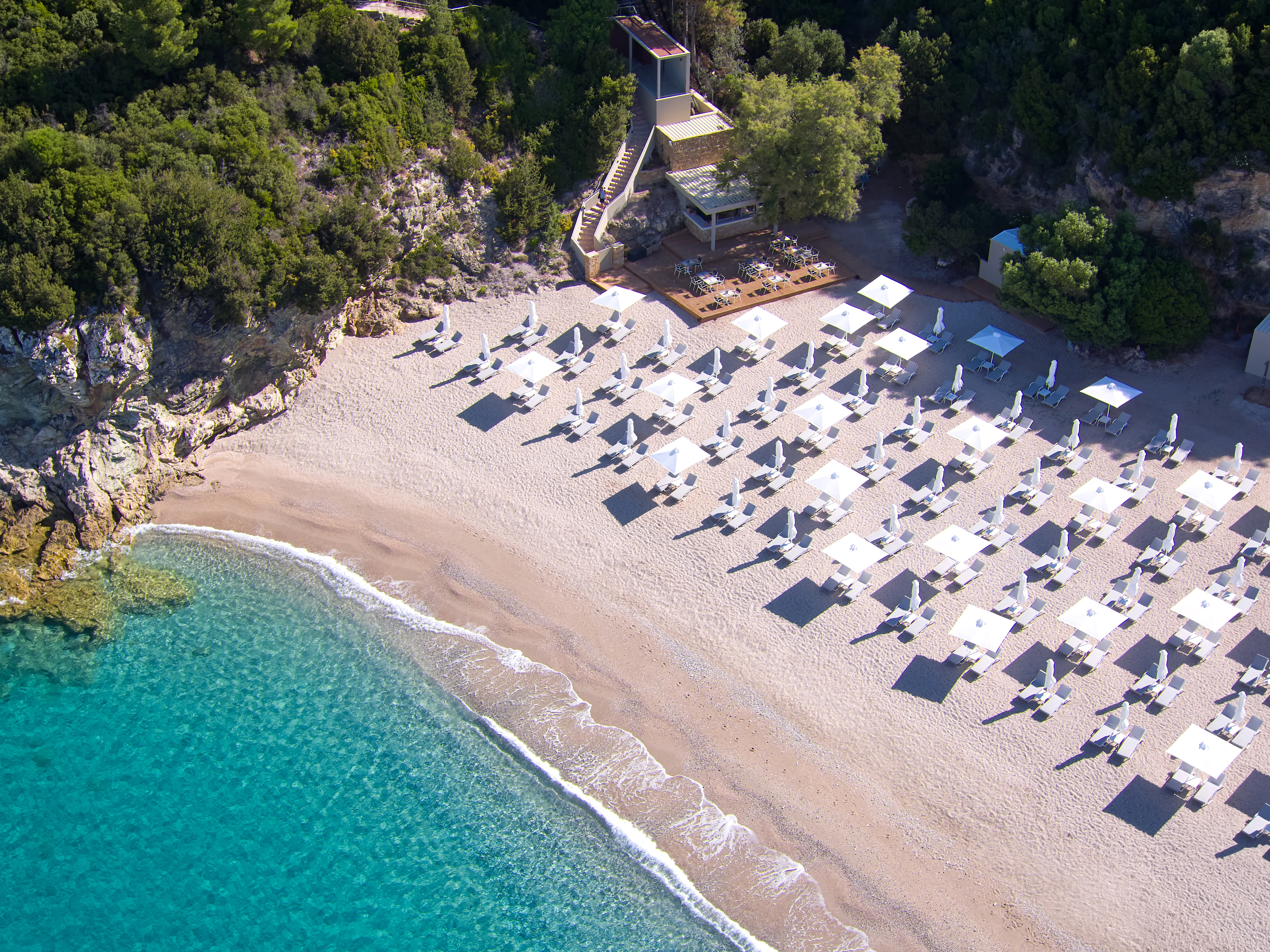 Vakker strand med hvite parasoller og krystallklart vann i Perdika og Karavostasi