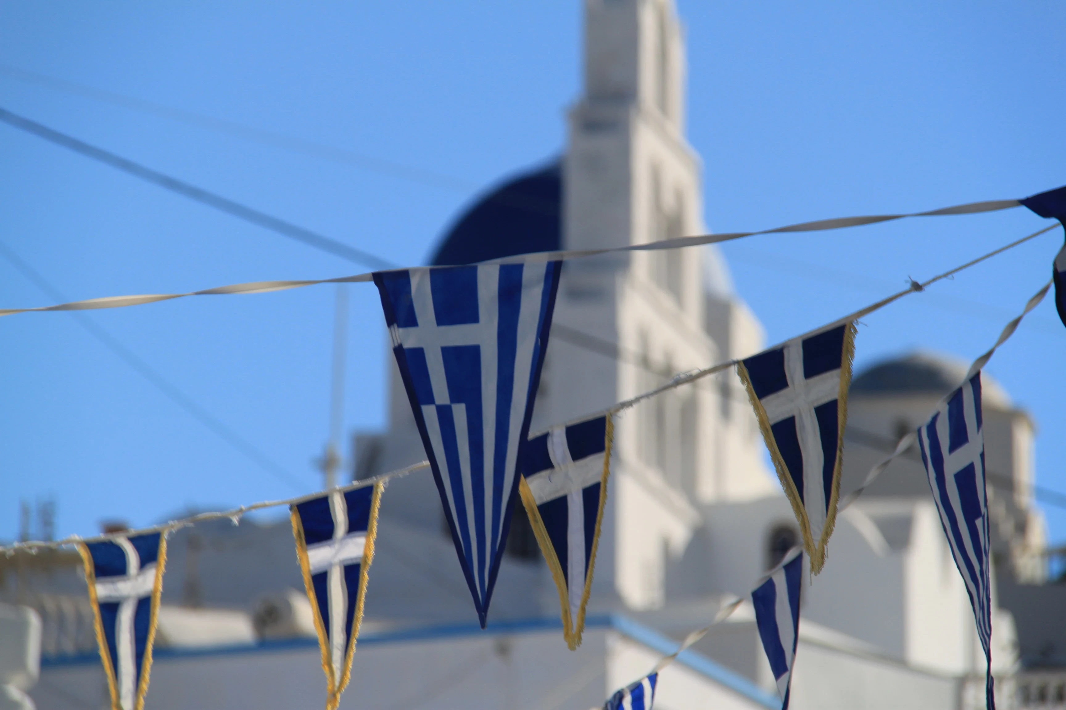 Vimplar med grekiska flaggan framför en kyrka på Mykonos