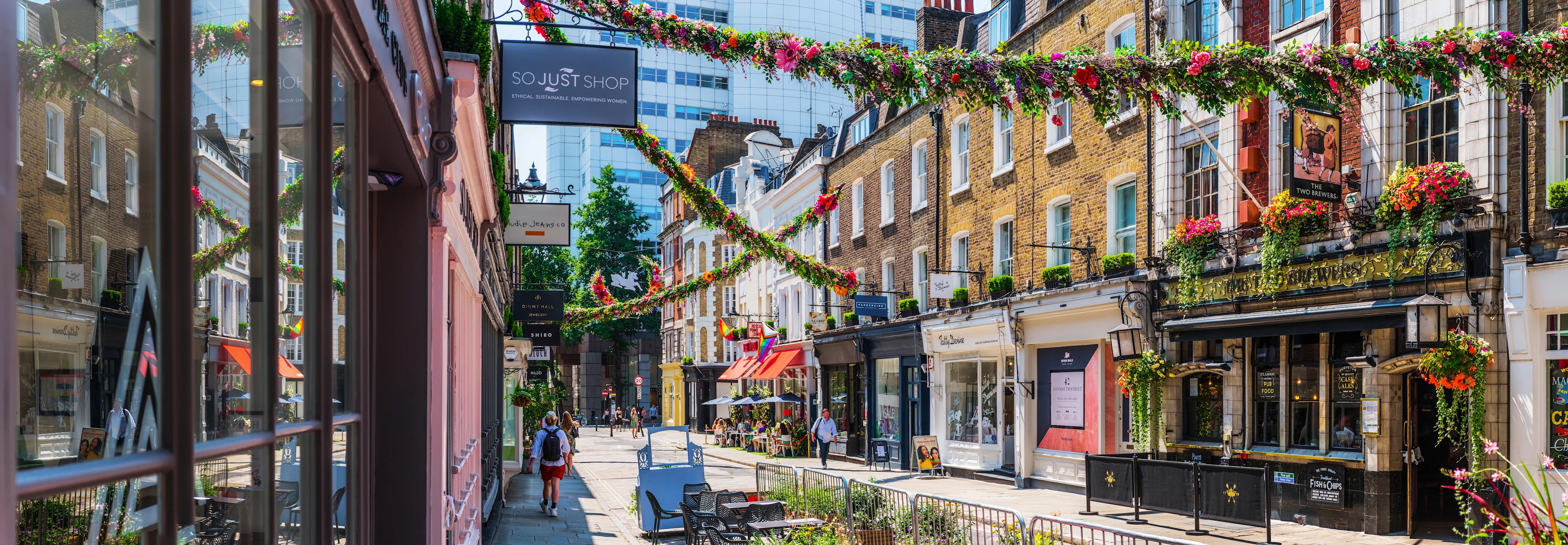 Gågata i London med butiker, tegelbyggnader och hängande blommor