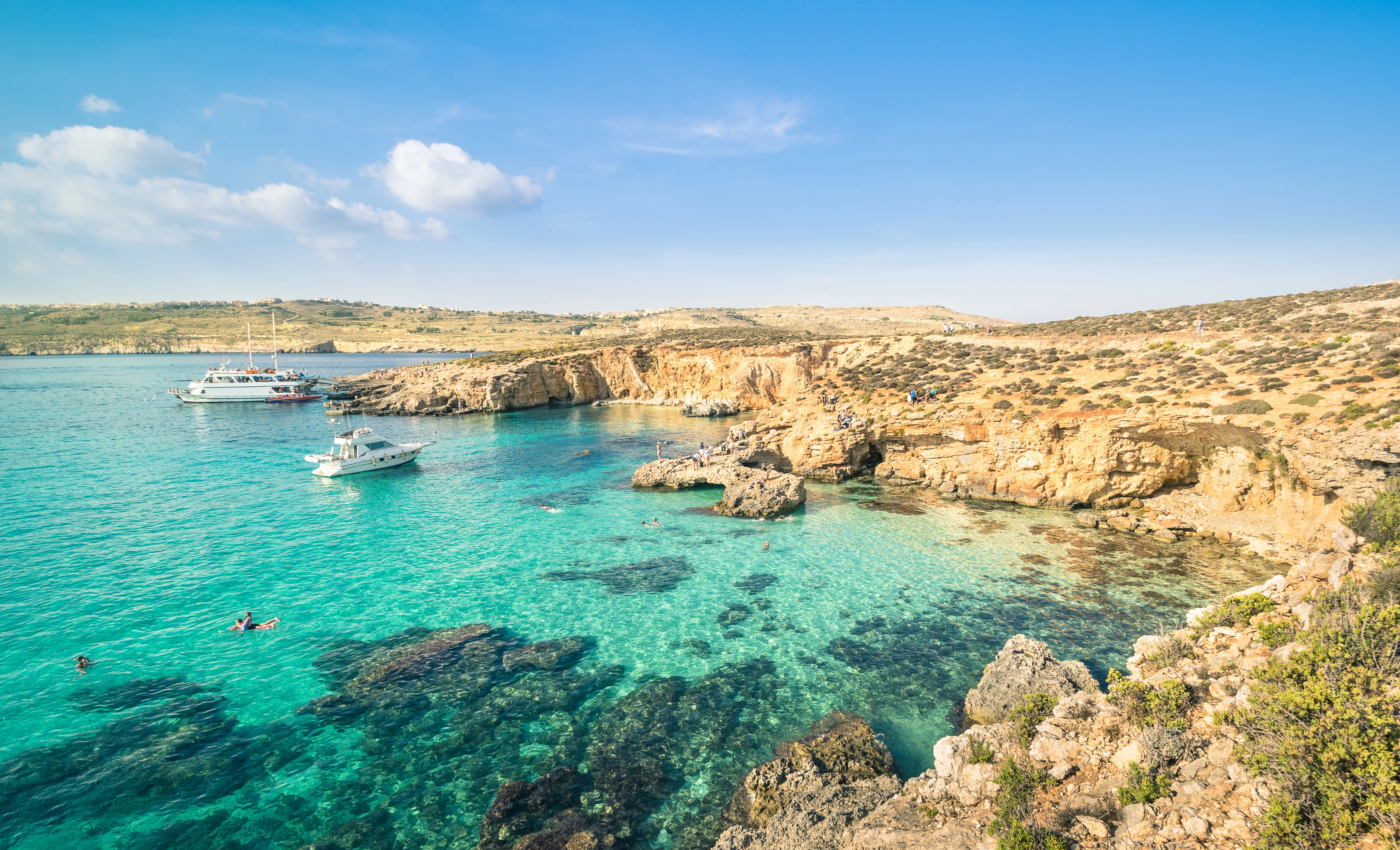 Blue Lagoon på Comino, Malta, med turkost vatten, klippkust och båtar i en av Medelhavets mest populära badvikar.