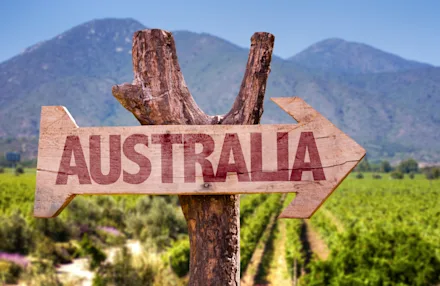 En skylt i trä med texten "Australia" framför en vingård