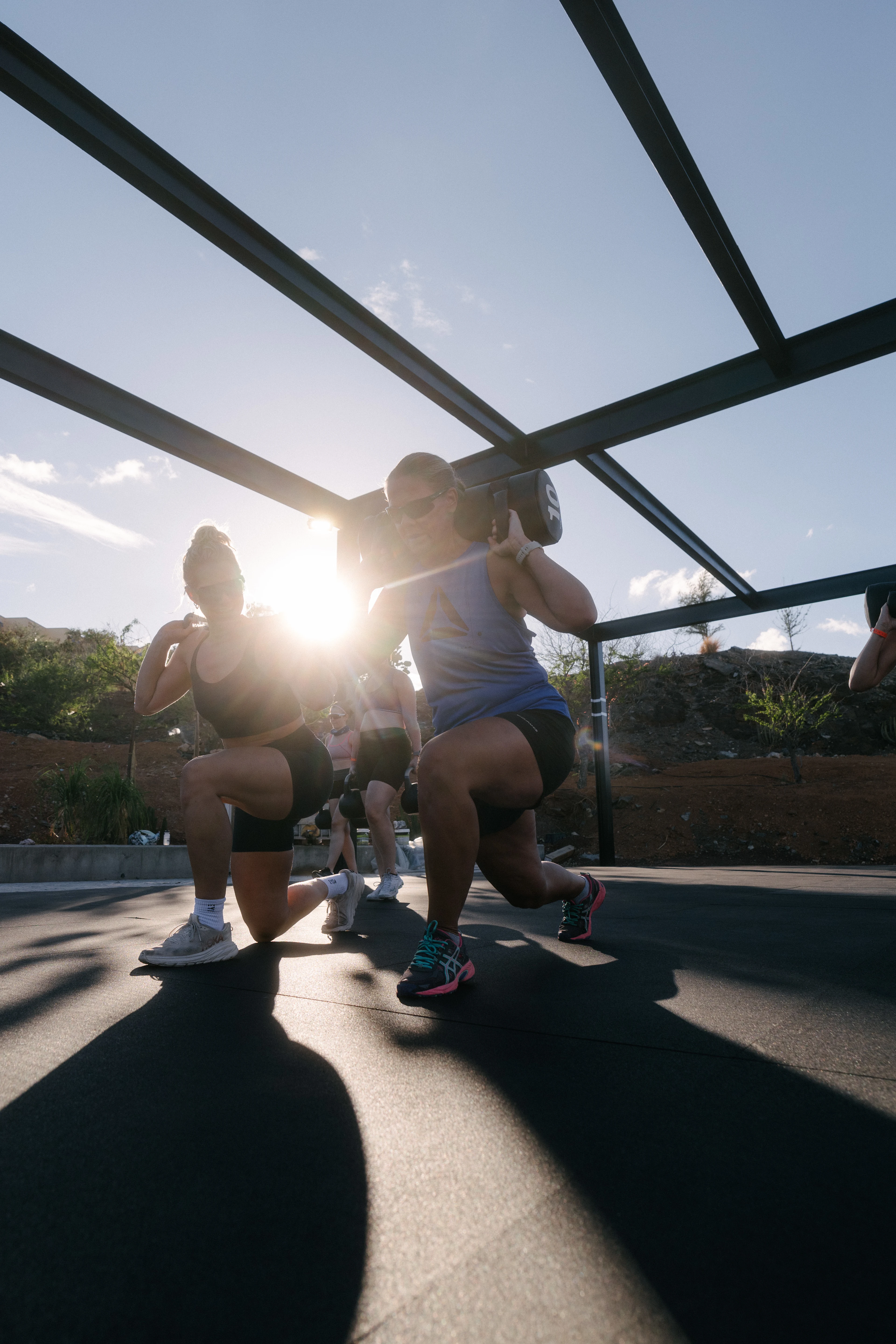 Catrine Collins instruerer en dame i blå topp og sort shorts i utfall med vekter