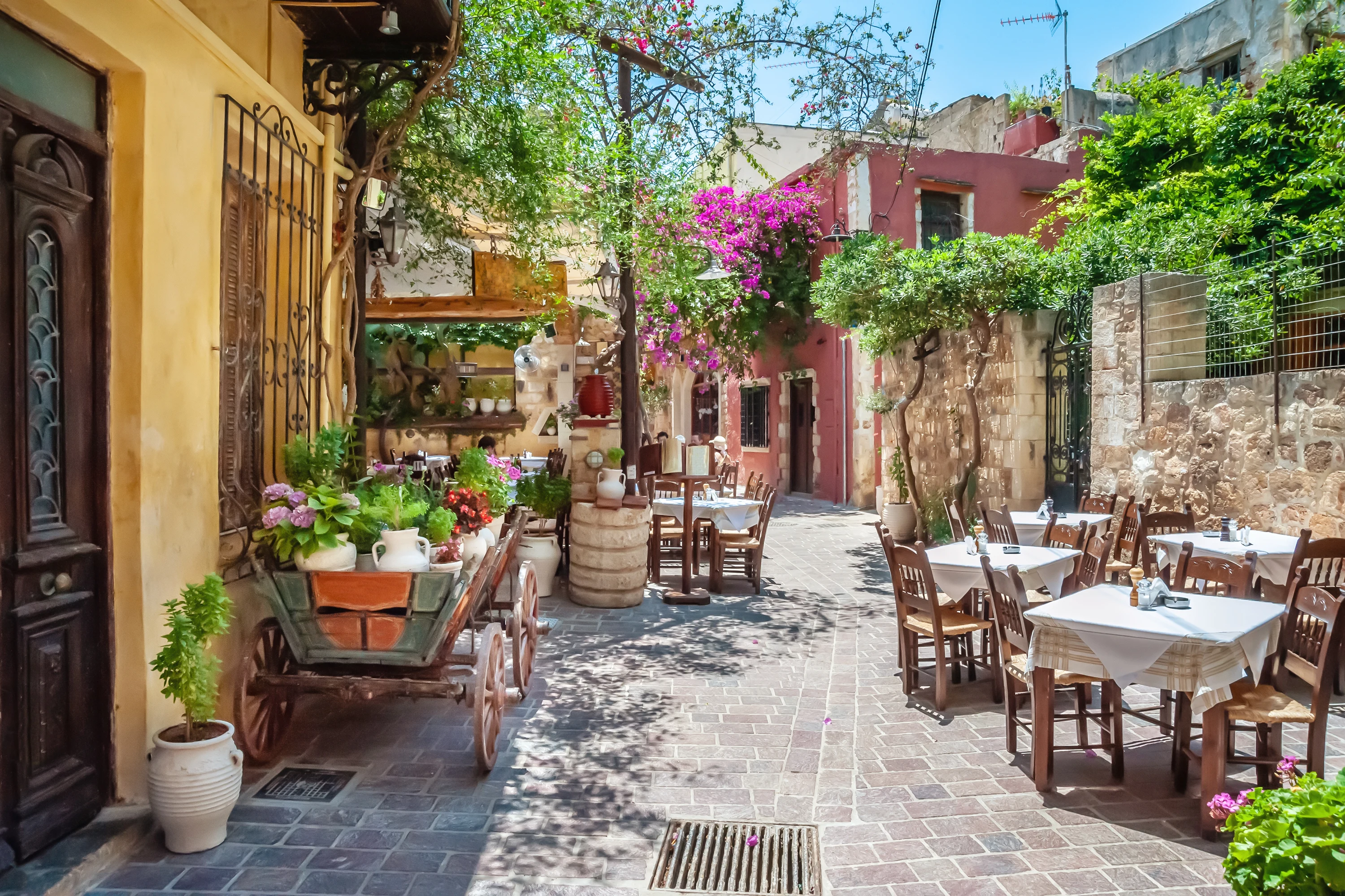 Mysig gata i gamla stan i Chania med uppdukade bord