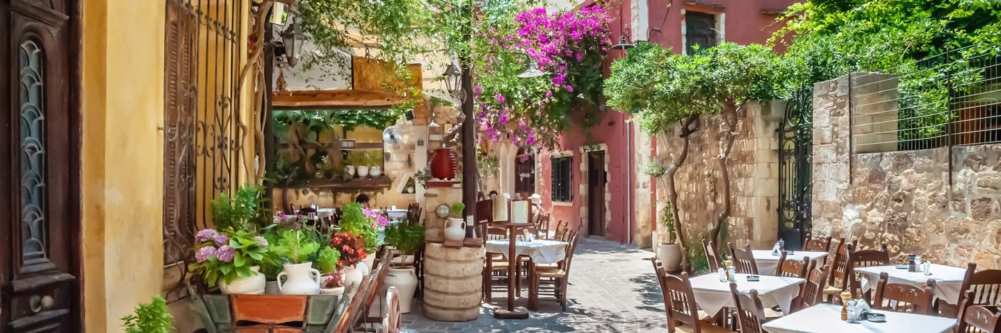 Mysig gata i gamla stan i Chania med uppdukade bord